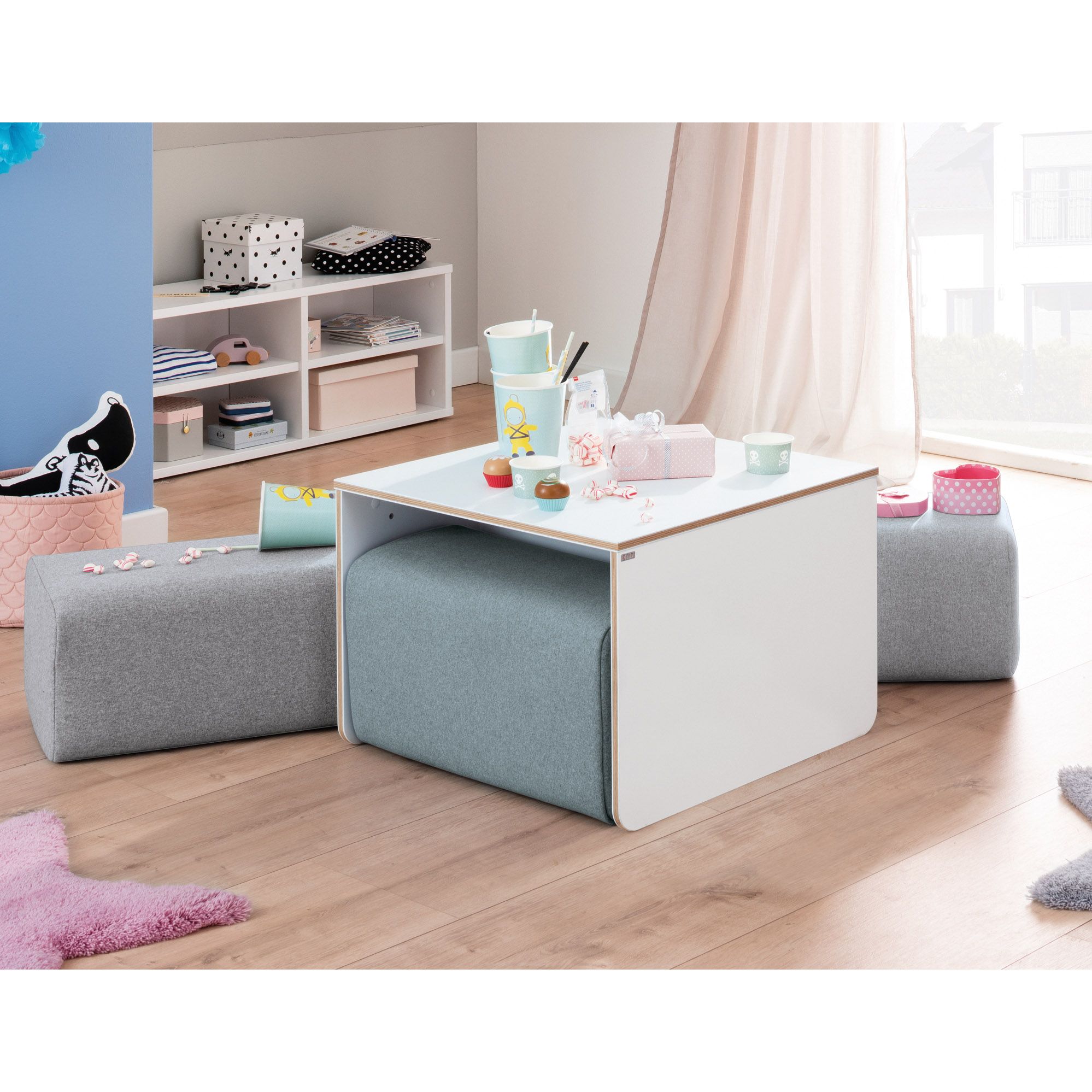 Kinderspieltisch mit Hockern, Spielzeug für die Teeparty und pastellfarbene Zimmerdekoration.