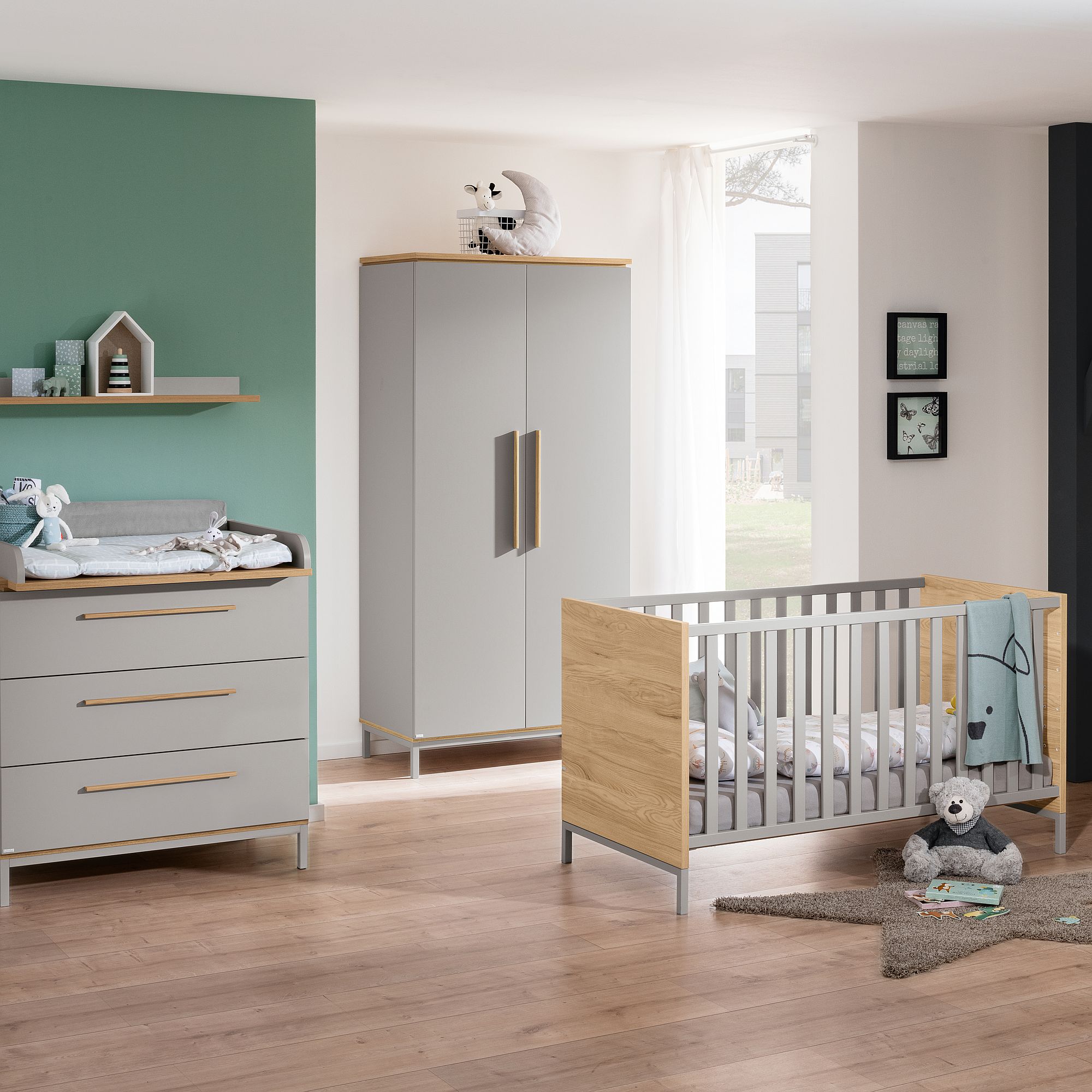 Modernes Babyzimmer mit einem grauen Kinderbett, einer Kommode, einem Kleiderschrank und Plüschtieren.
