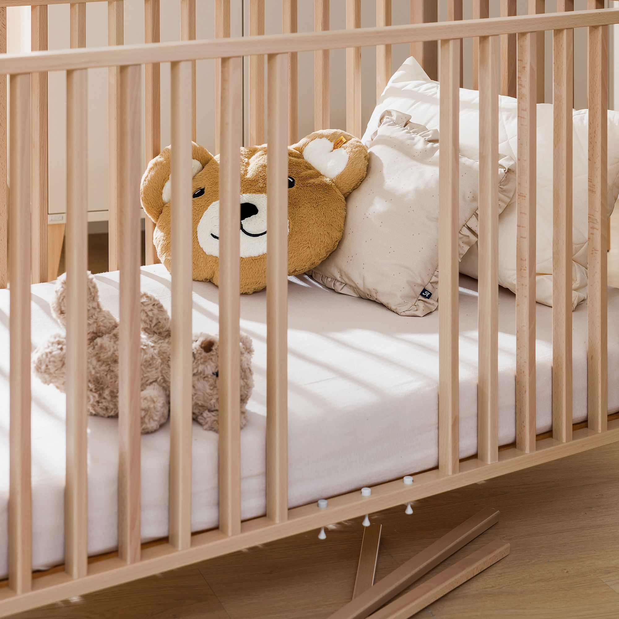 Eine Holzkrippe mit Kissen und einem teddybärförmigen Kissen im Inneren.
