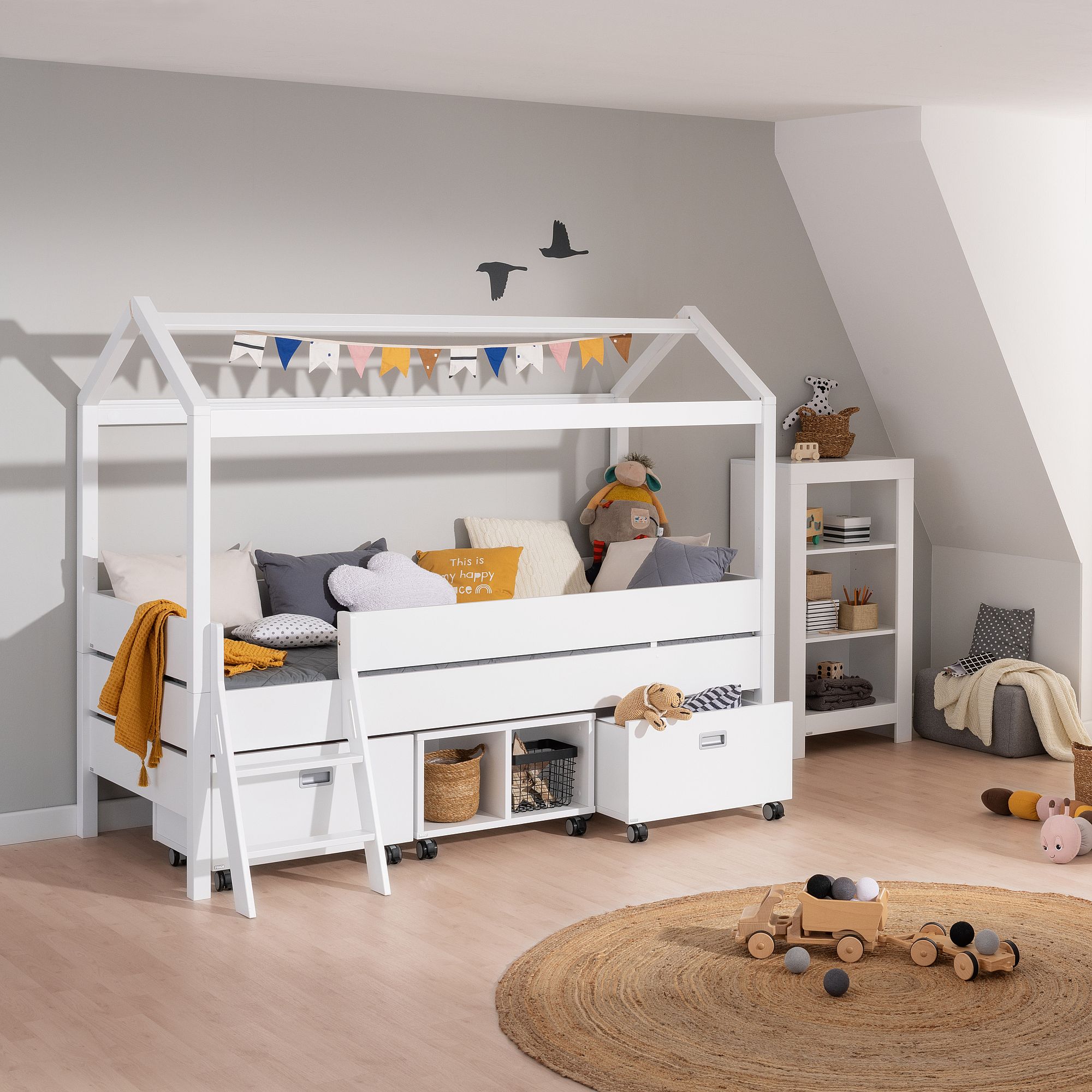 Kinderzimmer mit einem Bett mit Hausrahmen, Spielzeug und Regalen.