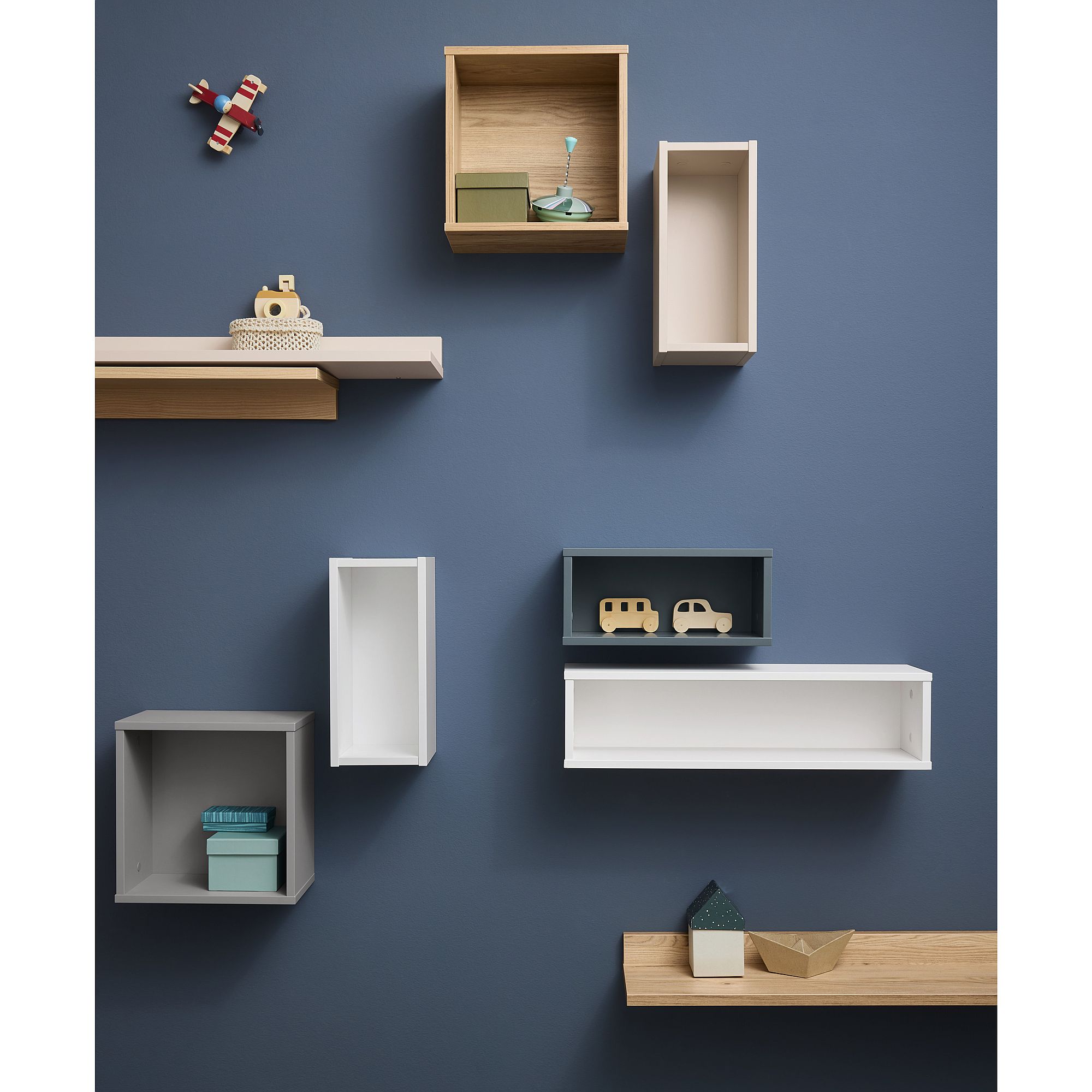 Verschiedene an der Wand befestigte Regale und Spielzeuge, die auf einer blauen Wand angeordnet sind.