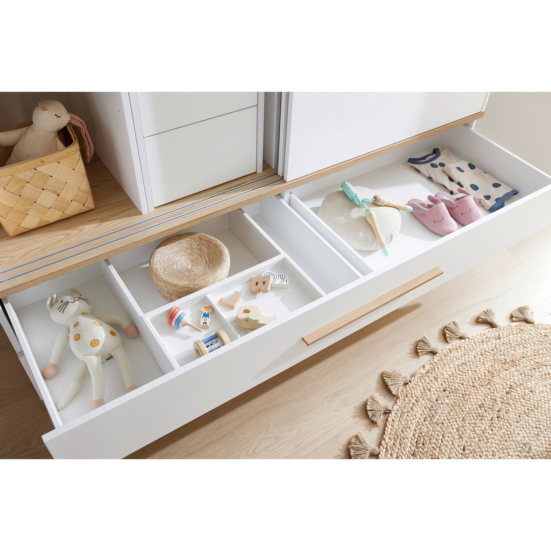 Schiebetürenschrank Yolanda mit 2 Schiebetüren und 2 Schubladen in 164 cm Offene Schublade mit ordentlich organisiertem Spielzeug, Babyschuhen und einem ausgestopften Häschen.