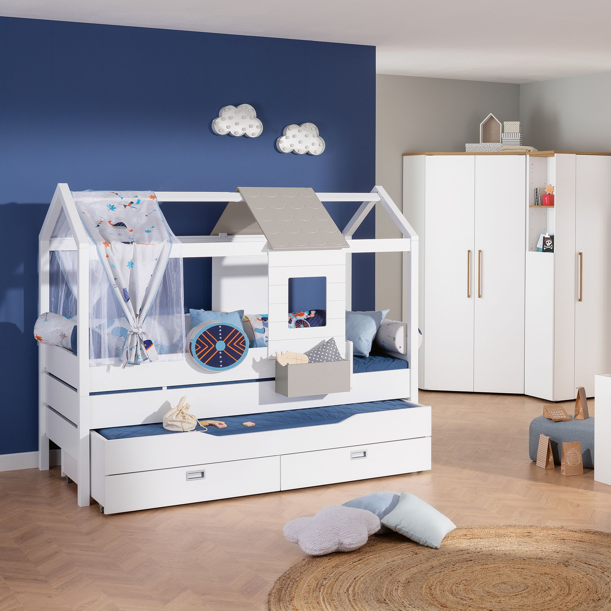 Kinderzimmer mit einem Bett mit Hausrahmen, blauen Akzenten und Wolkendekor.