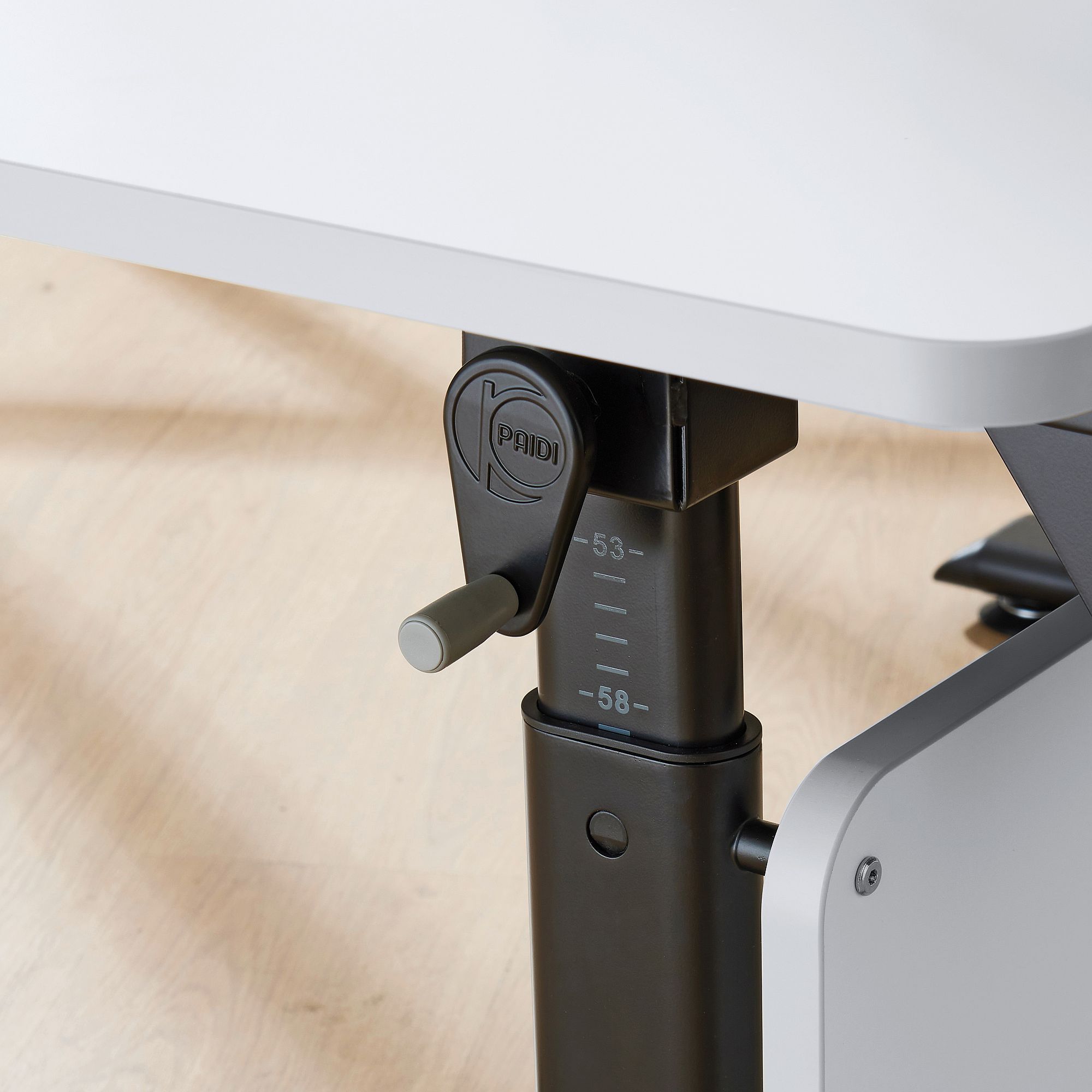 Nahaufnahme einer Tischhöhenverstellkurbel mit Messmarkierungen.