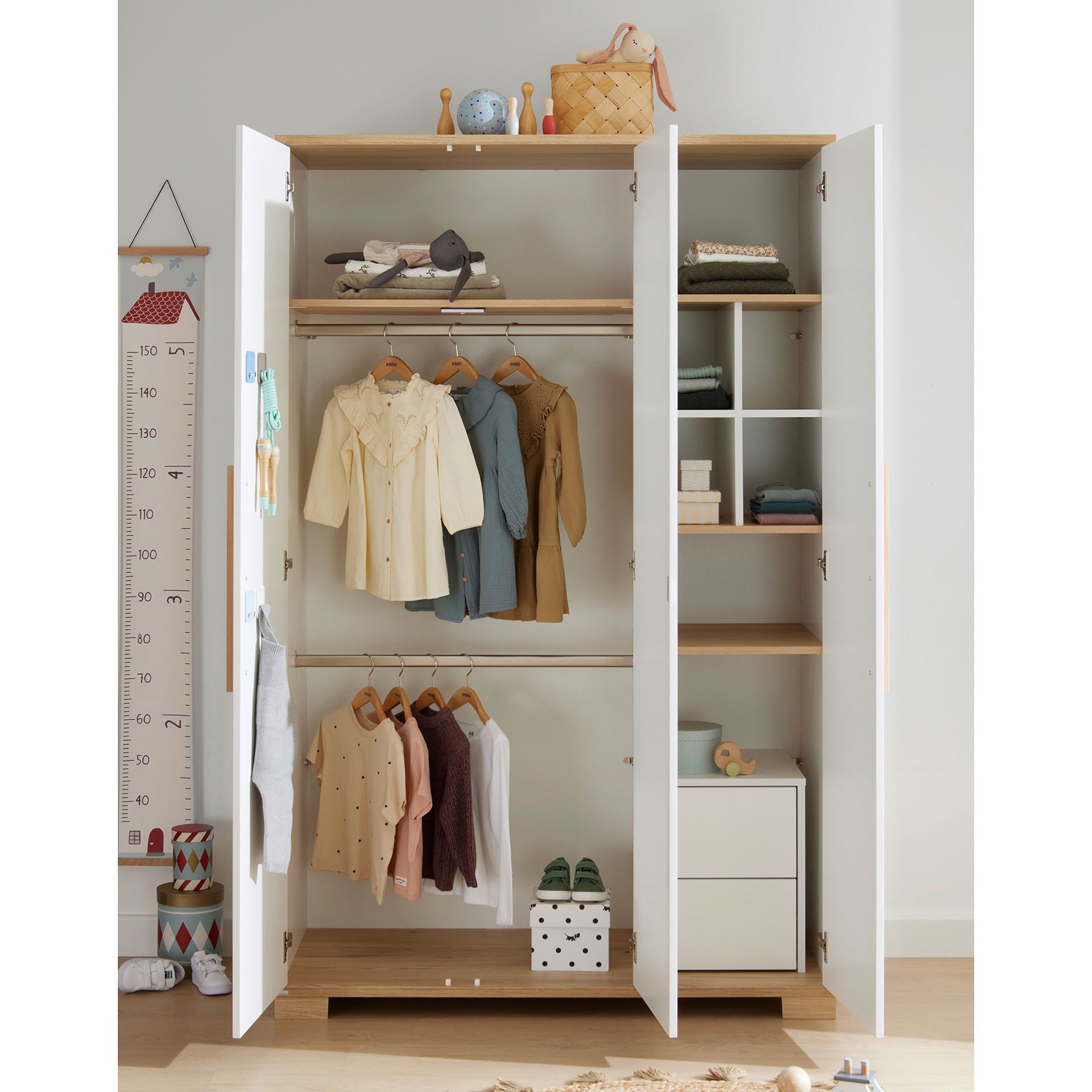 Drehtürenschrank Yolanda mit 3 Türen Offener Kleiderschrank mit Kinderkleidung, Spielzeug und ordentlich gefalteten Gegenständen darin.