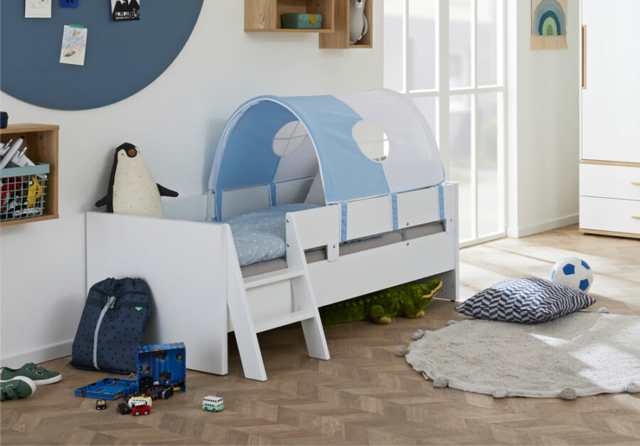 Children’s bed with a blue and white tent canopy, ladder, plush toys, and soccer ball in a bright, modern room.