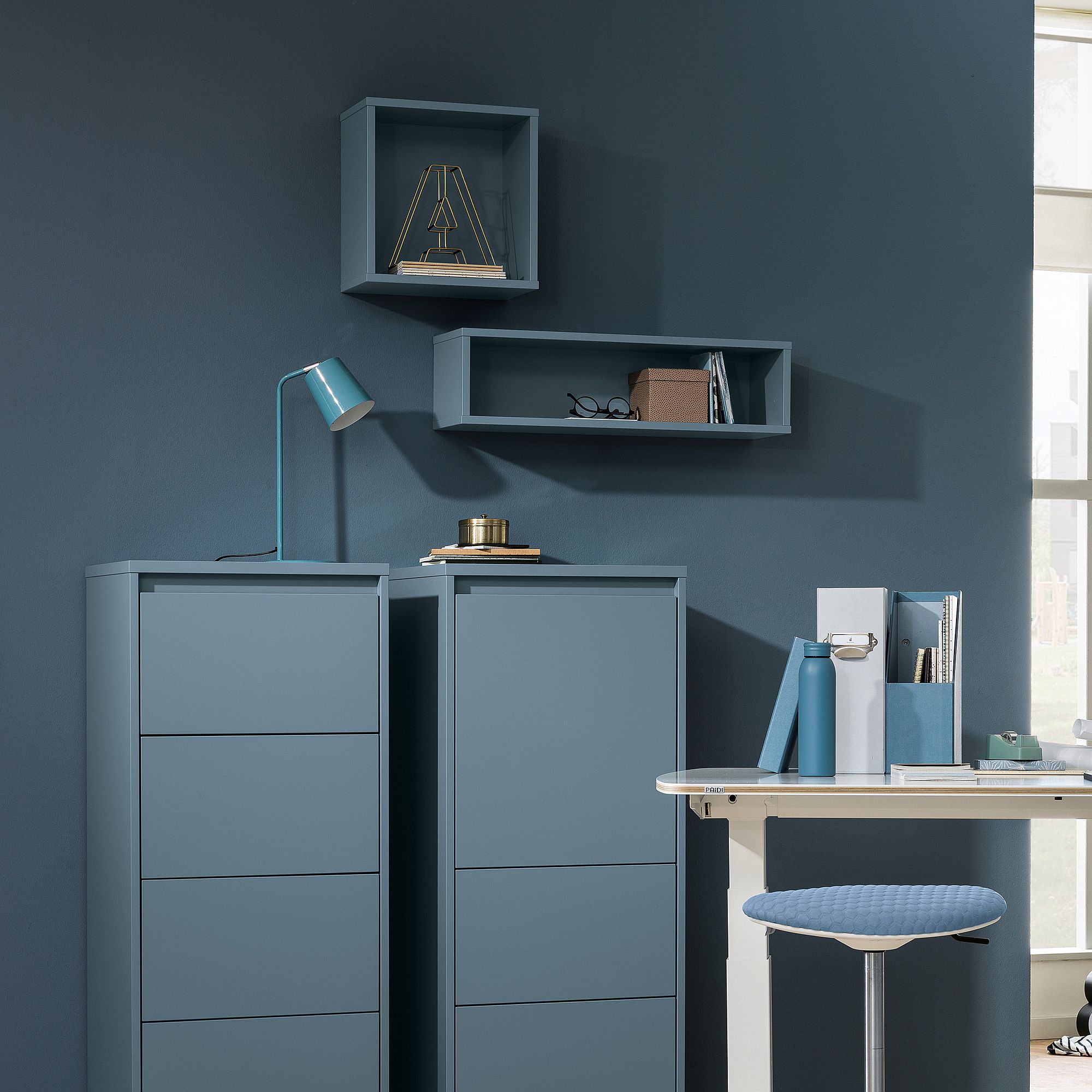 Wandregal  Wandbox  rechteckig lang in Mattblau Modernes blaues Büro mit Regalen, Schubladen, Lampe und Büchern vor blauer Wand.