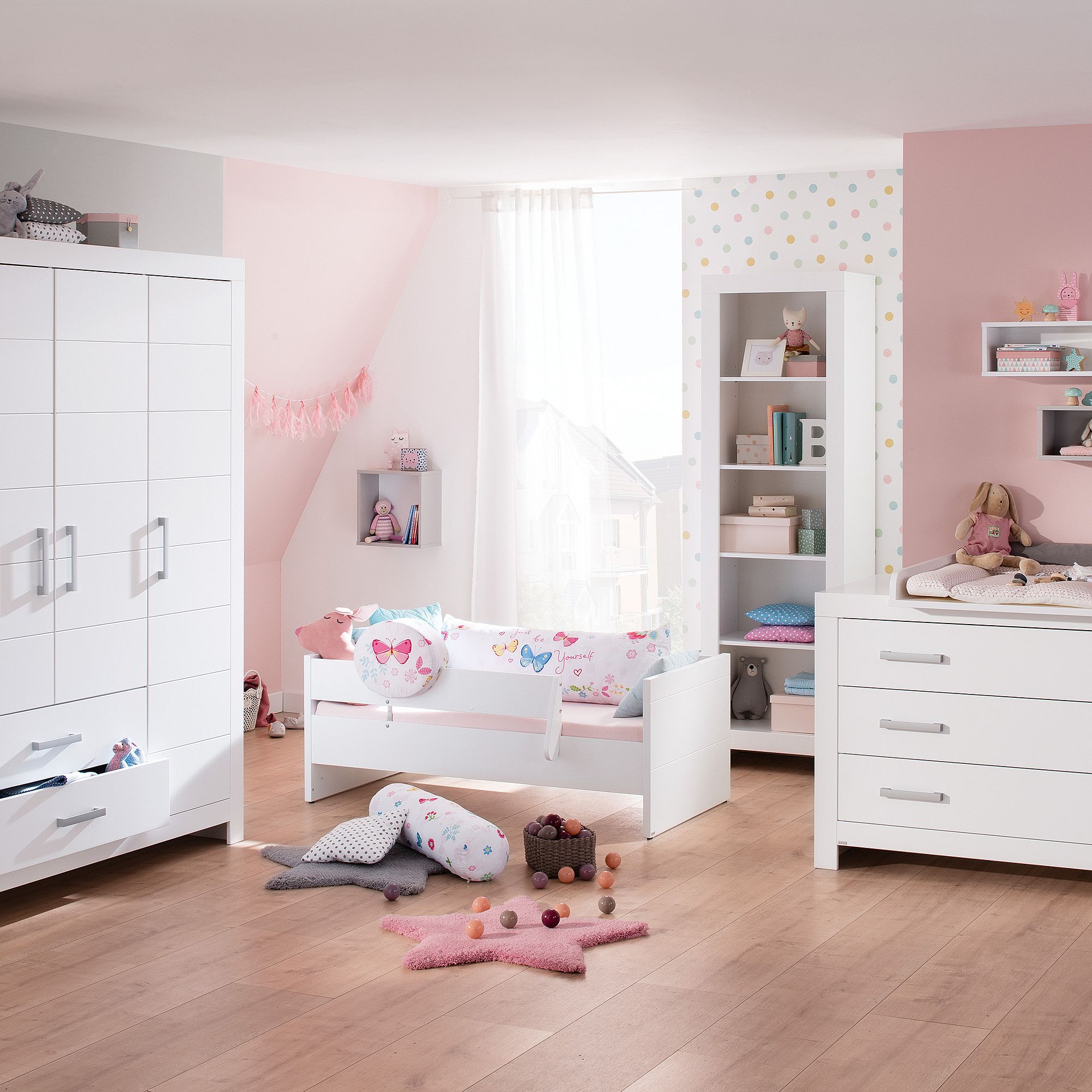 Bright, modern kids bedroom with pastel decor, white furniture, and wood floor.
