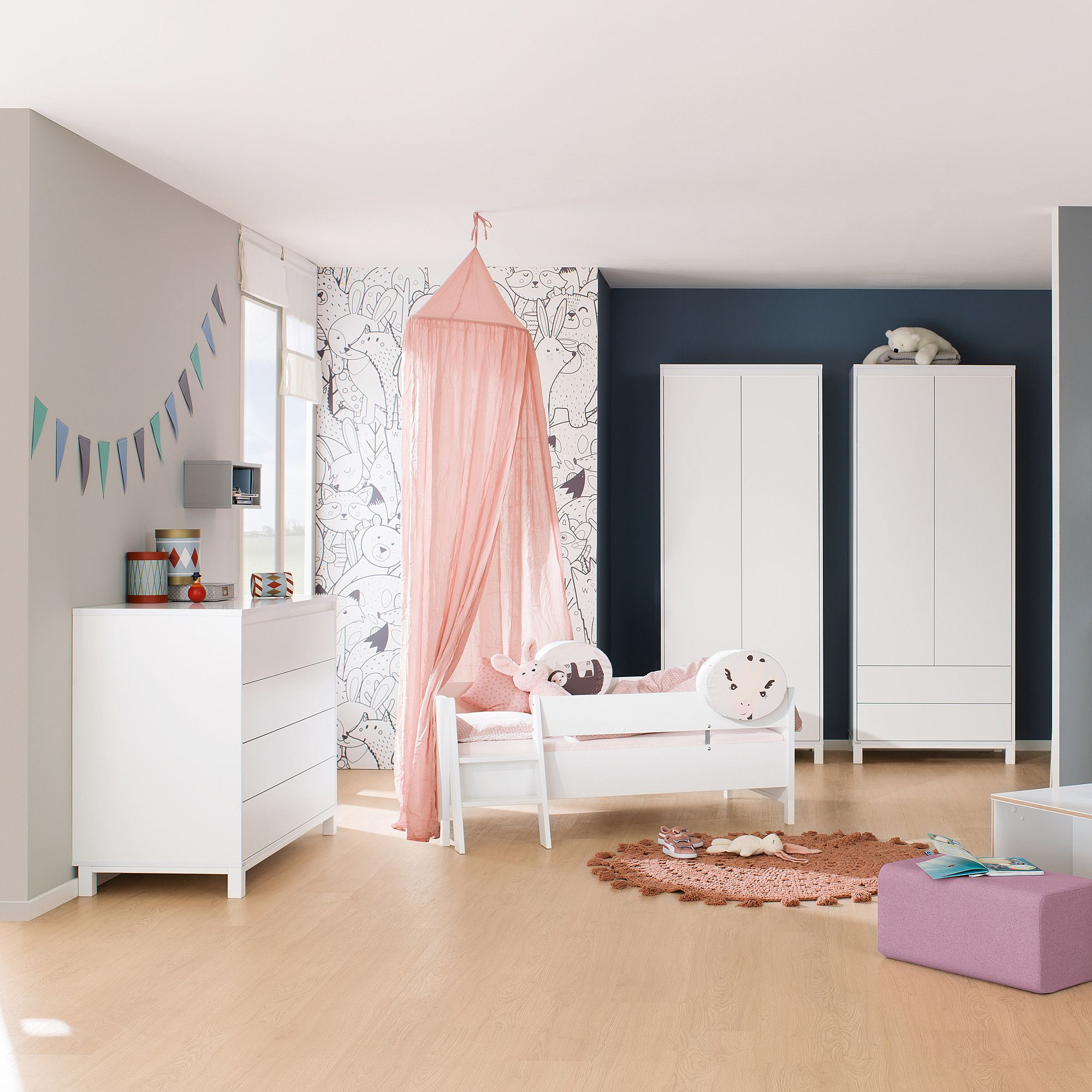 Ein Kinderzimmer mit weißen Möbeln, einem rosa Baldachin und verspieltem Dekor.
