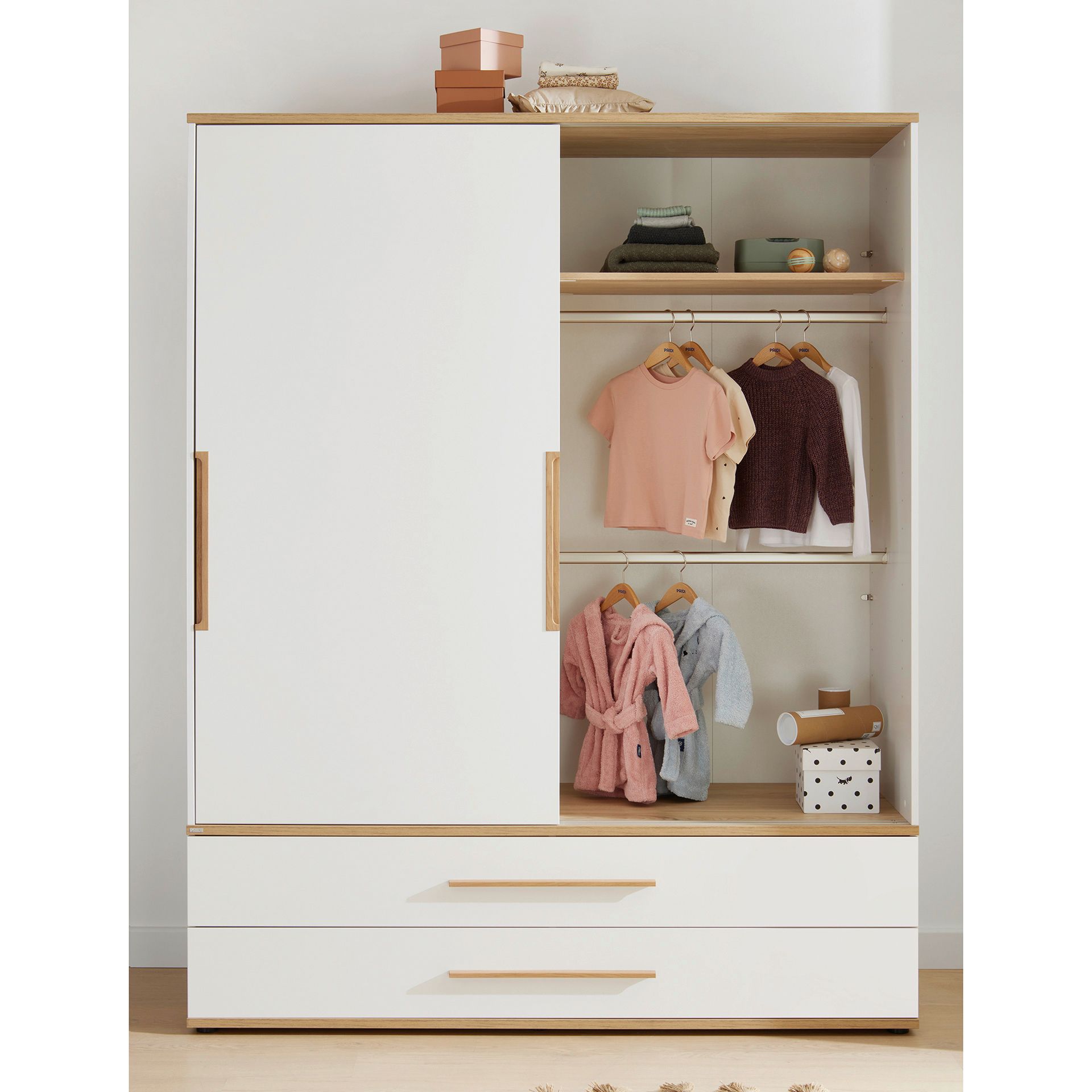 A modern white wardrobe with wooden accents, two large drawers, and open shelves displaying childrens clothes, folded towels, storage boxes, and hanging shirts and jackets.