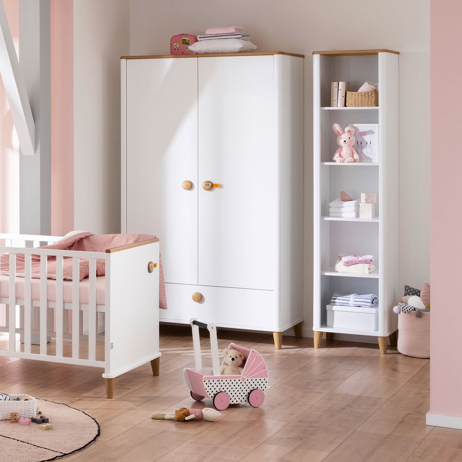 Drehtürenschrank Lotte & Fynn - Steiff by PAIDI 2 Türen, 1 Schublade A pastel nursery with a crib, wardrobe, bookshelf, and a toy stroller.