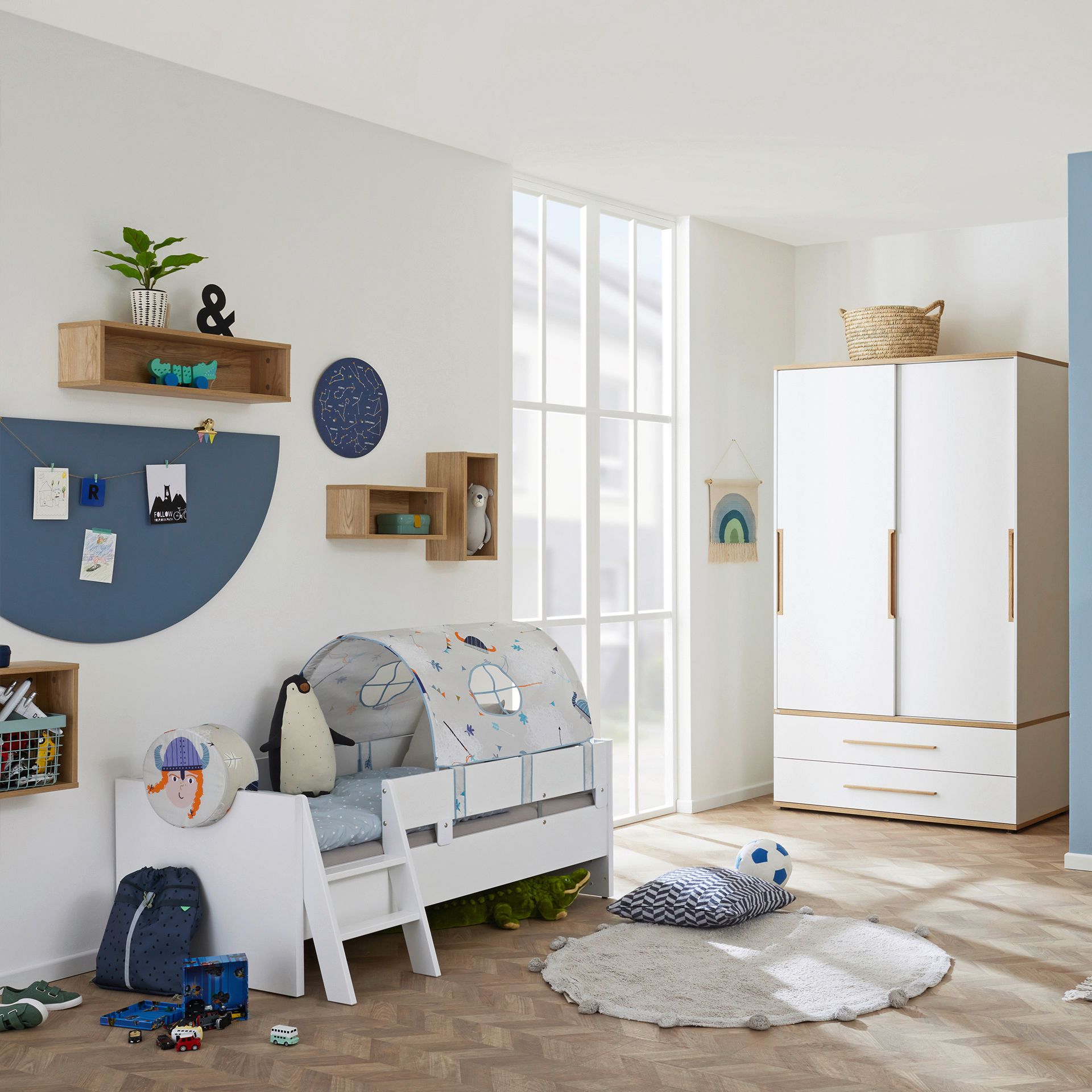 Modern childrens bedroom with a bed, wardrobe, toys, and wall shelves.