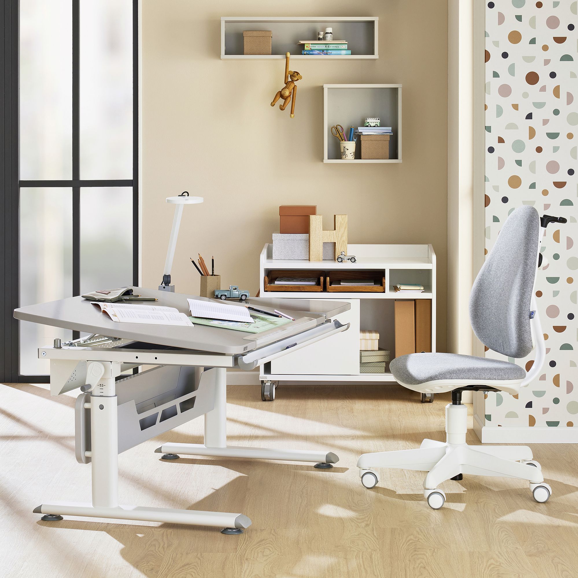 Modern childrens study desk and chair with shelves and toys in a bright room.