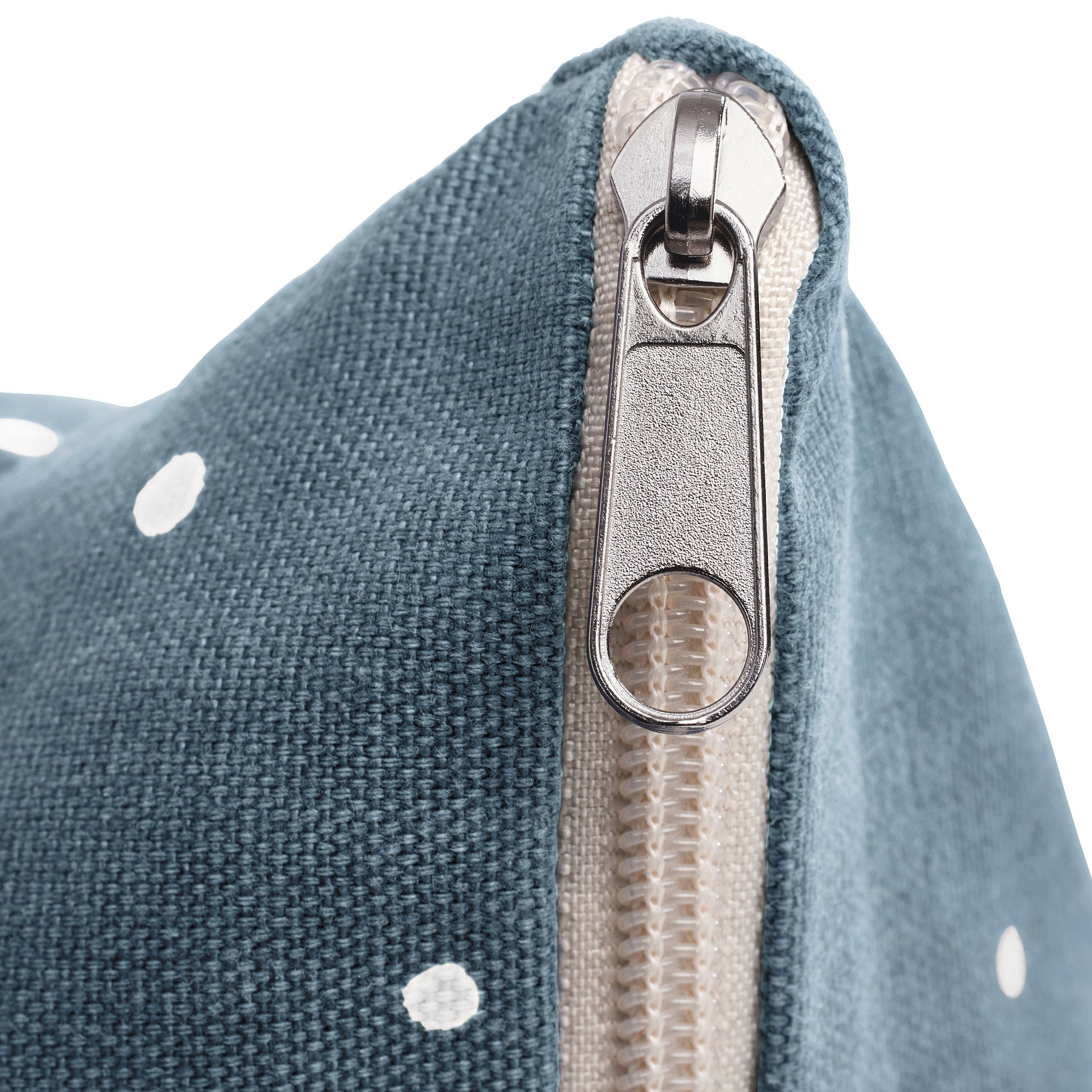 Nahaufnahme eines Reißverschlusses auf blauem Stoff mit weißen Tupfen.