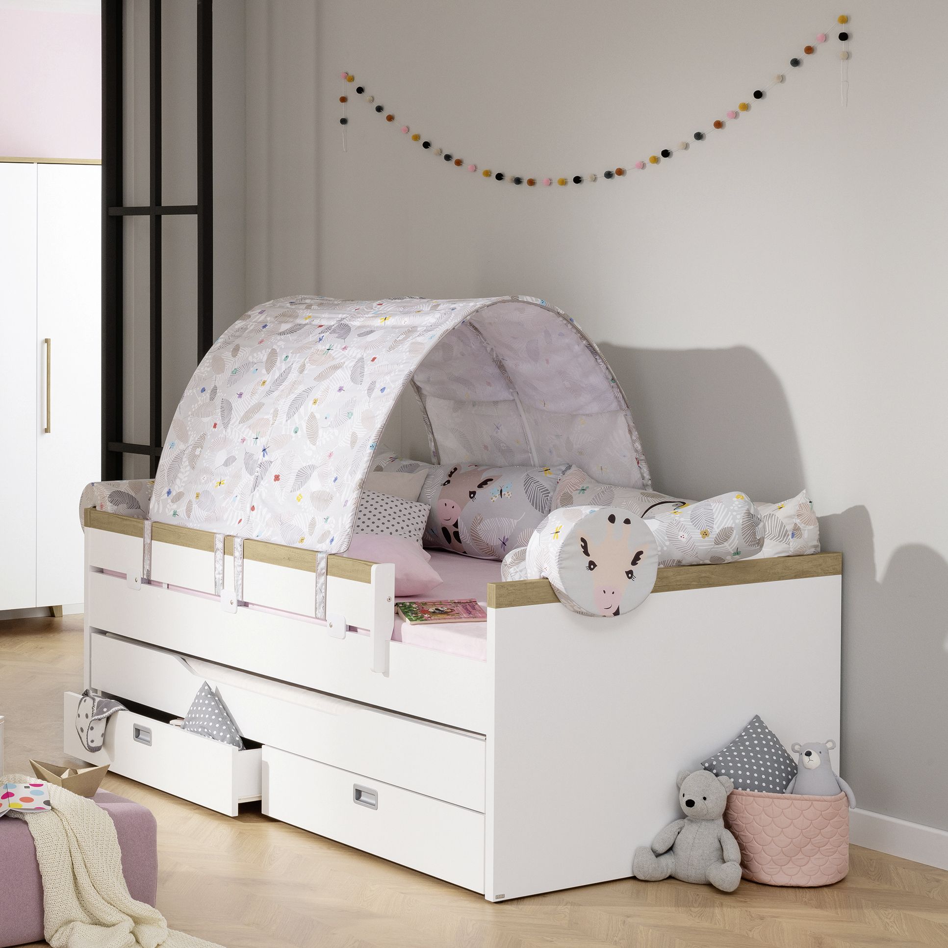 Childrens bed with canopy, animal pillows, and toys in a cozy room.