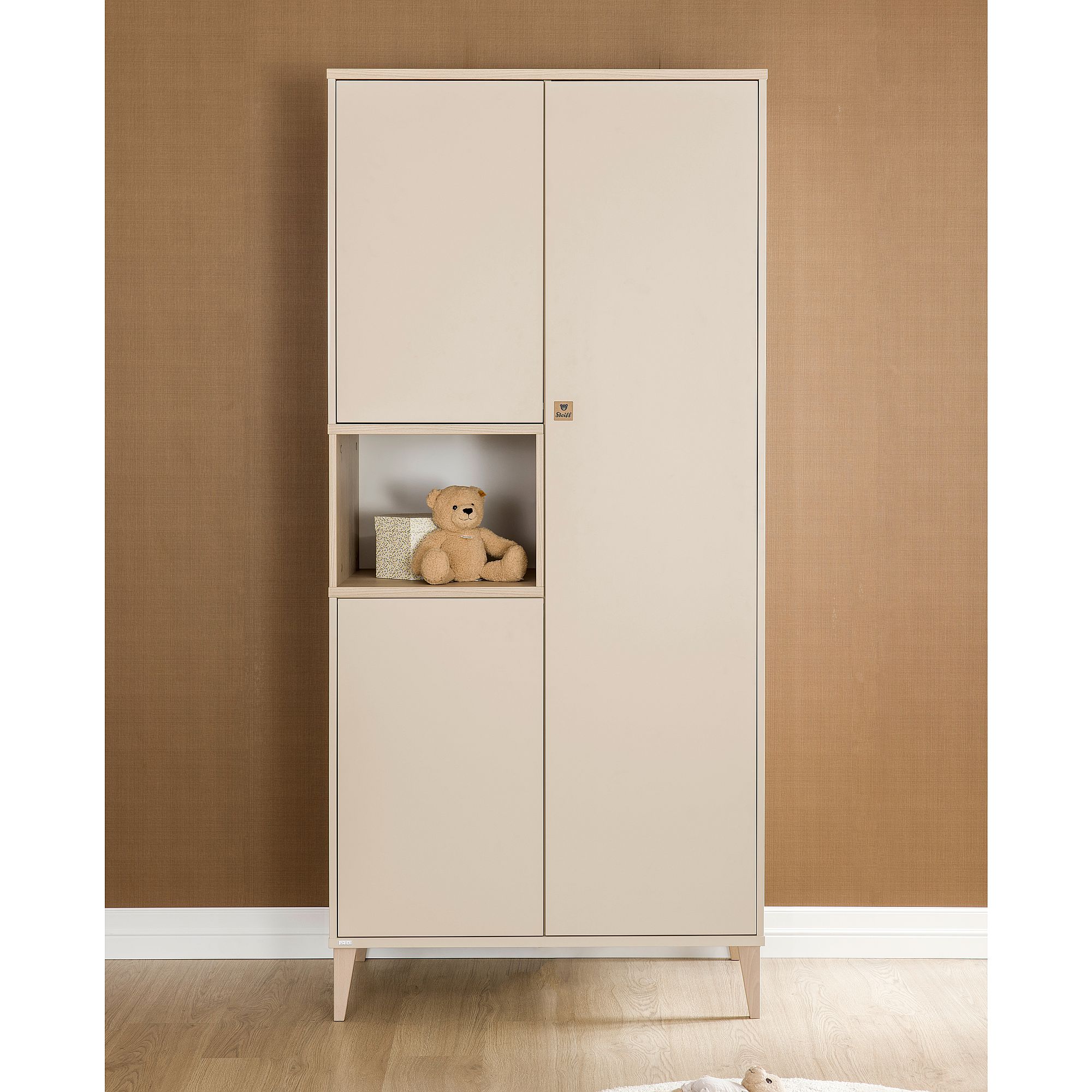 Hoher beiger Schrank mit einem Teddybären und einer kleinen Schachtel auf einem offenen mittleren Einlegeboden.