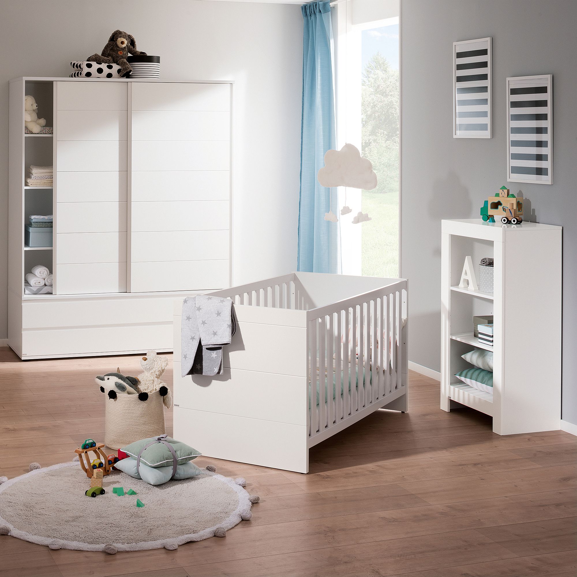 Modernes Kinderzimmer mit weißen Möbeln, einem Kinderbett, Spielzeug und einem blauen Vorhang am Fenster.