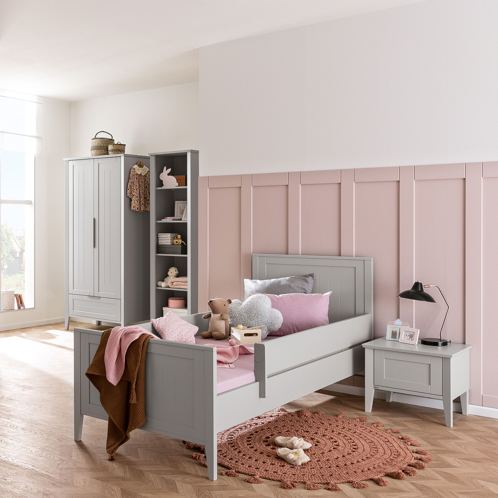 Children’s bedroom with gray furniture, pink bedding, and stuffed animals.