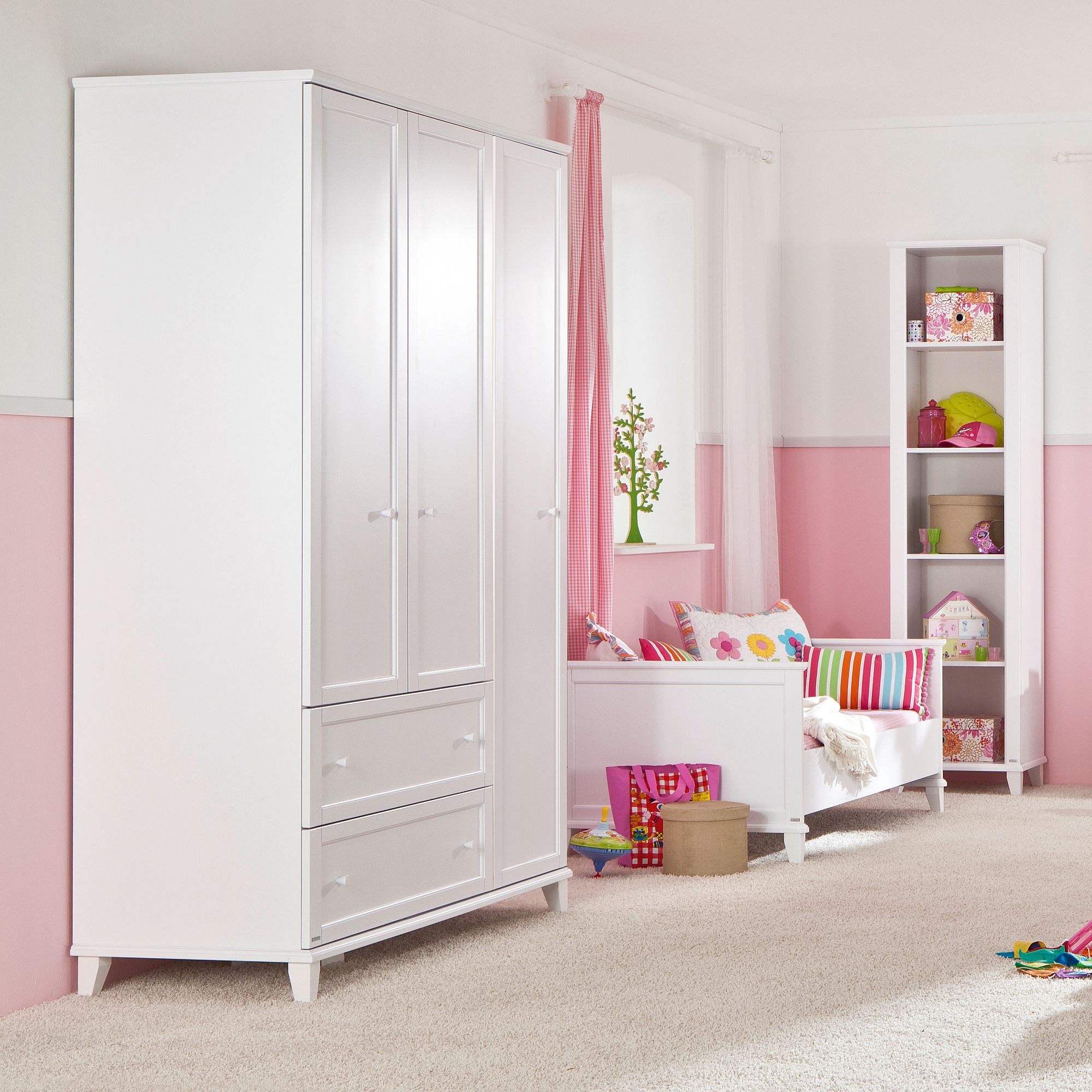 White kids’ room furniture set against pink and white walls with colorful accents.