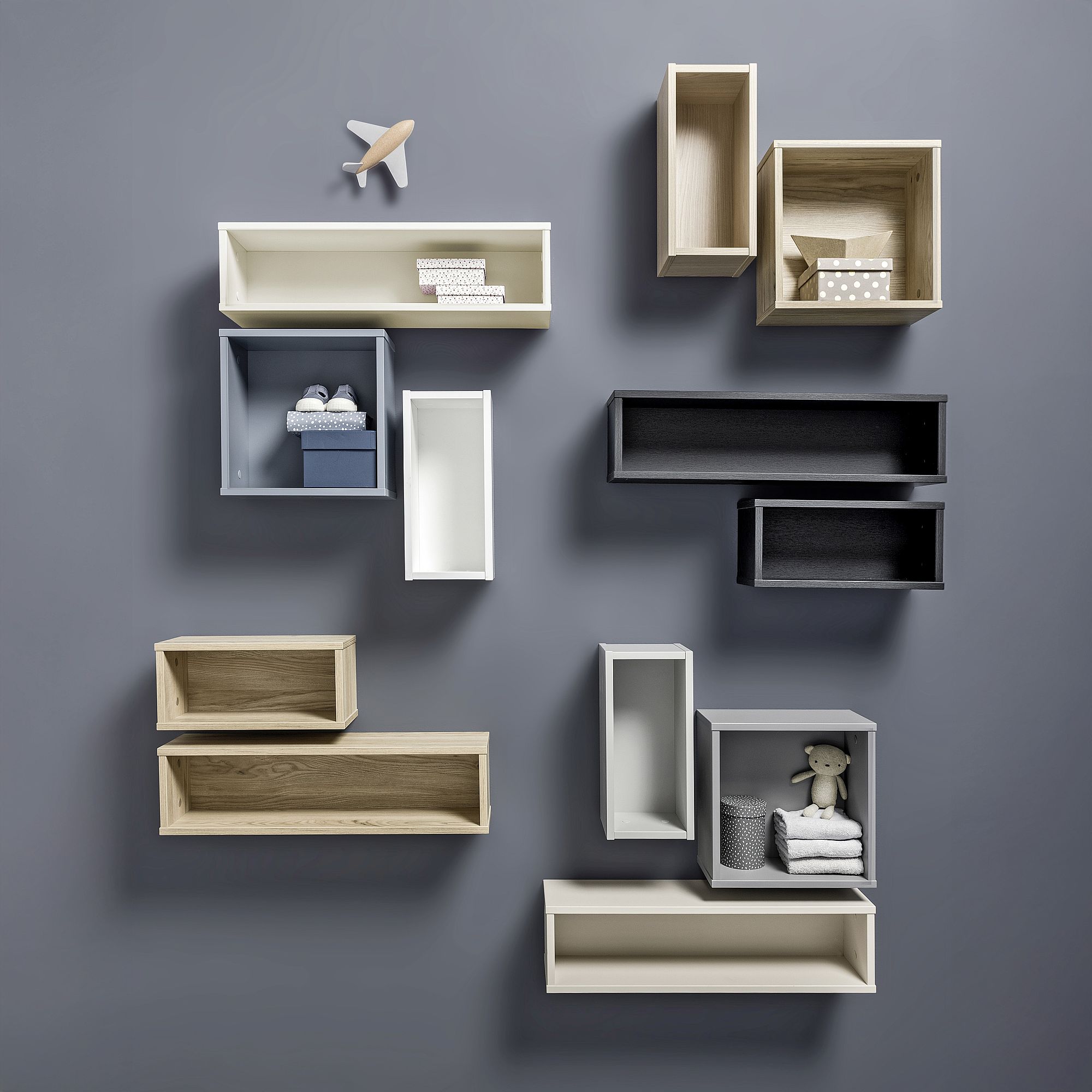 Wall shelves of various shapes and colors holding small toys and decor items.