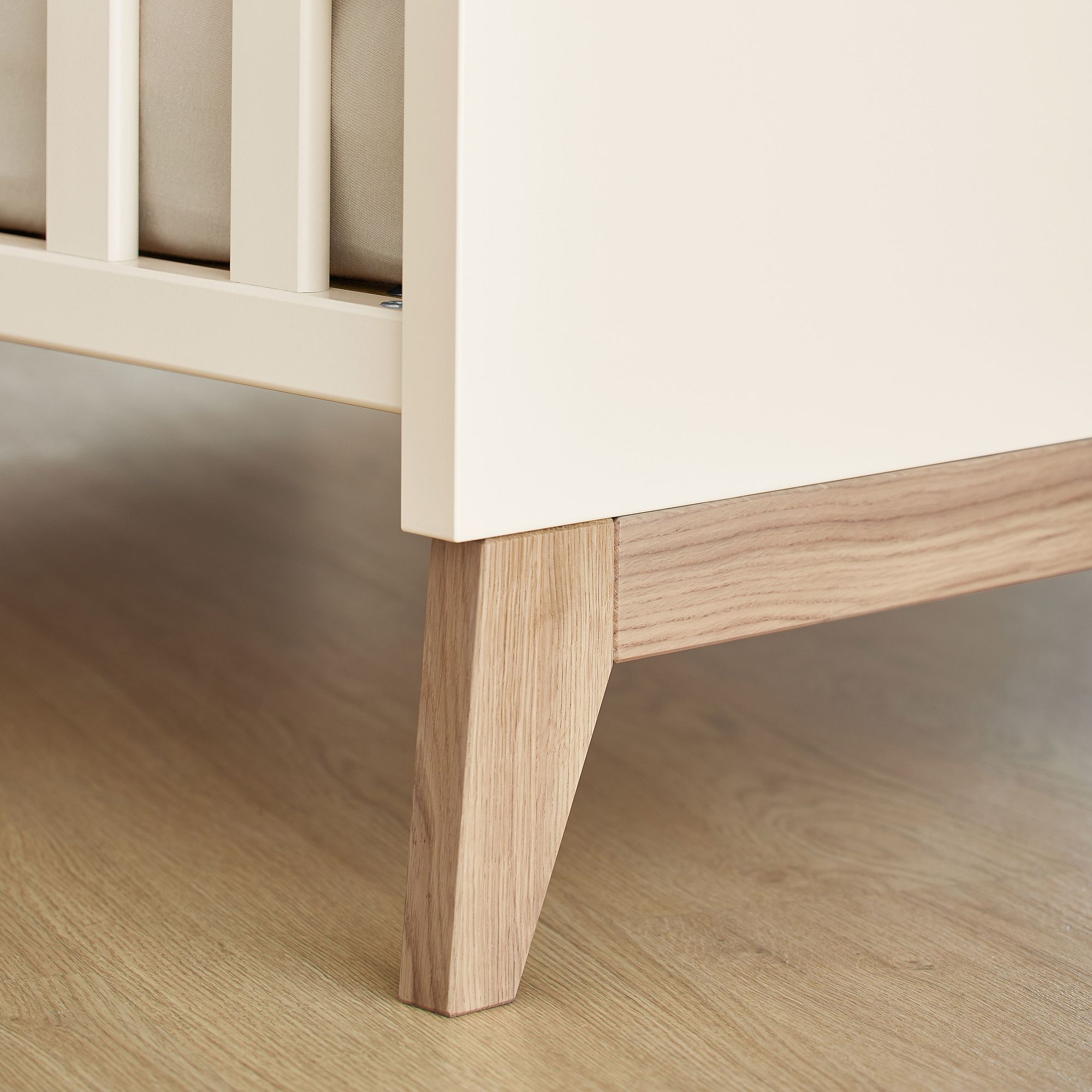 Nahaufnahme eines hölzernen Krippenbeins auf einem hellen Holzboden.