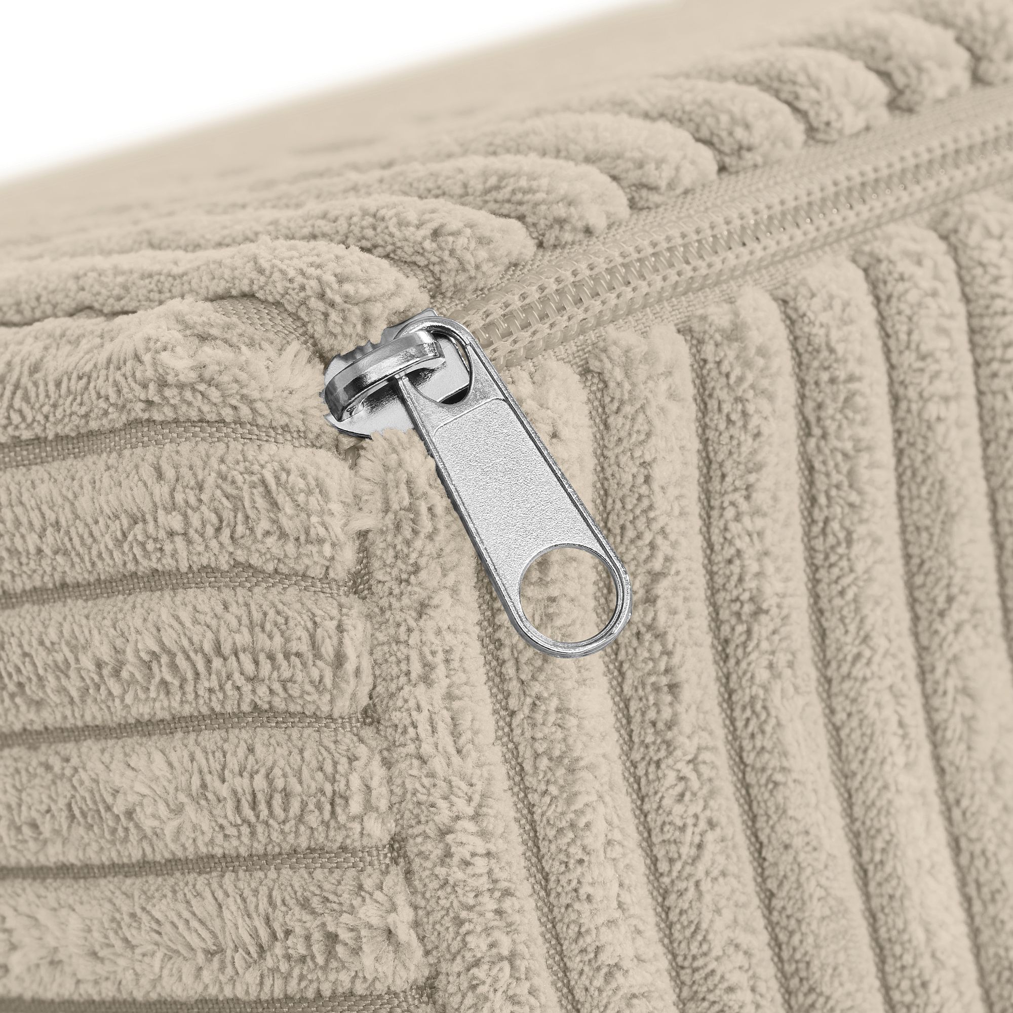 Nahaufnahme eines beigen, gerippten Stoffkissens mit einem silbernen Reißverschluss.