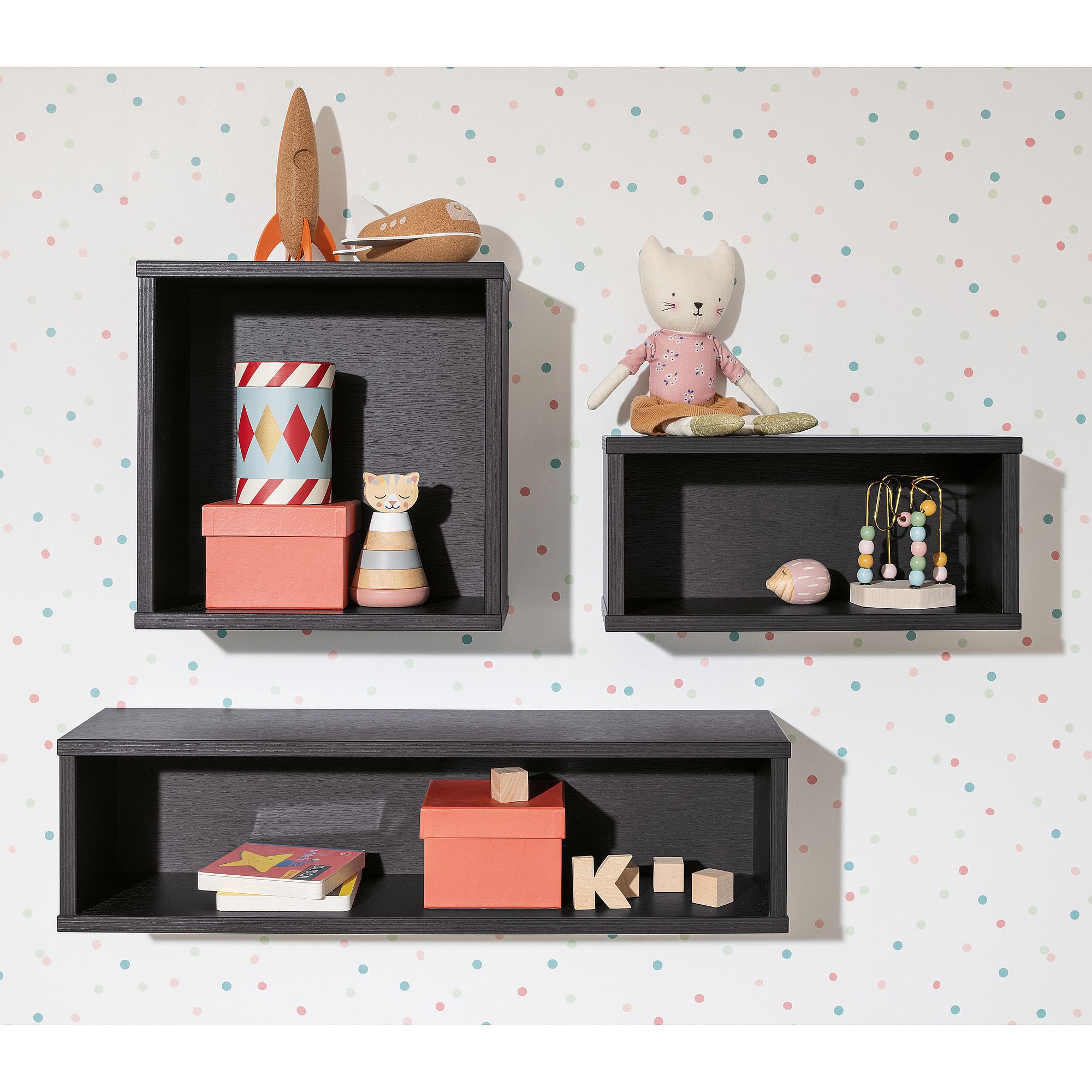 Wandregal  Wandbox  quadratisch in Naturschwarz Drei schwarze Wandregale mit Spielzeug, Büchern und Kisten vor einer gepunkteten Wand.