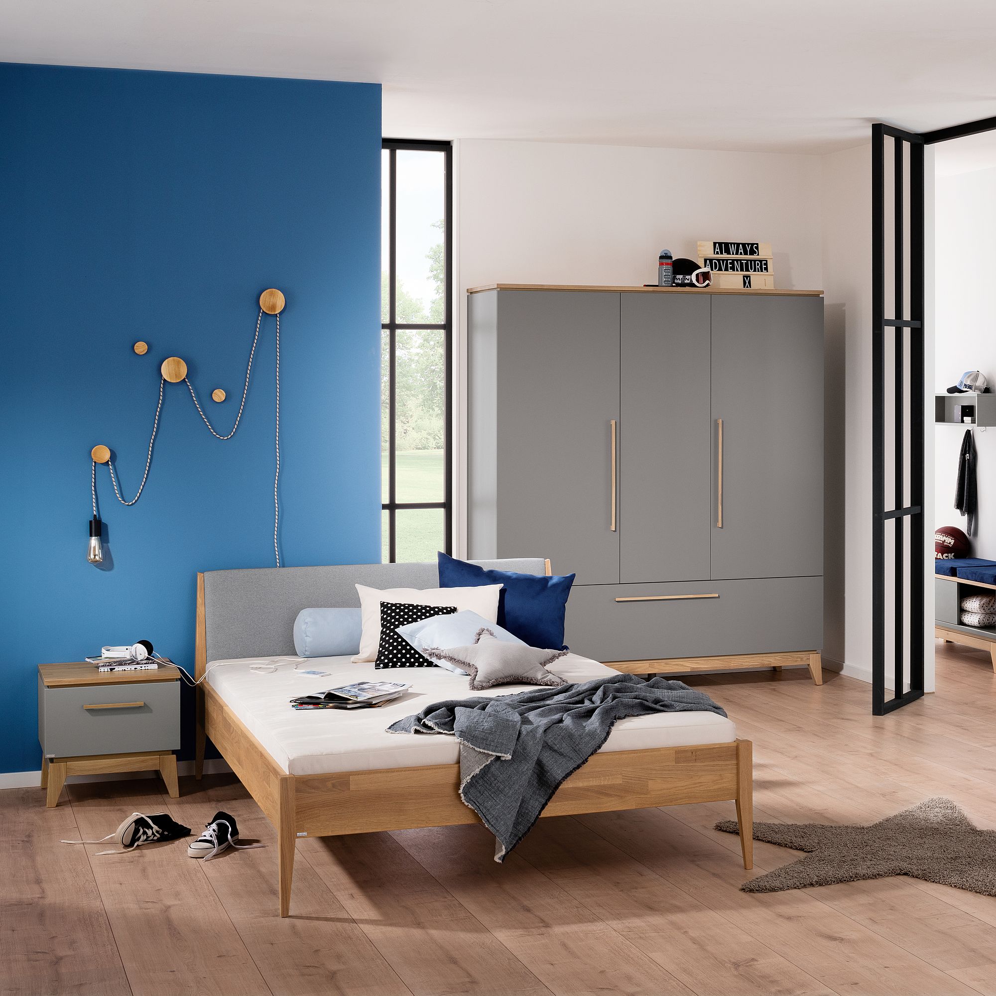Modernes Schlafzimmer mit einer blauen Akzentwand, grauen Möbeln und einem ungemachten Bett.