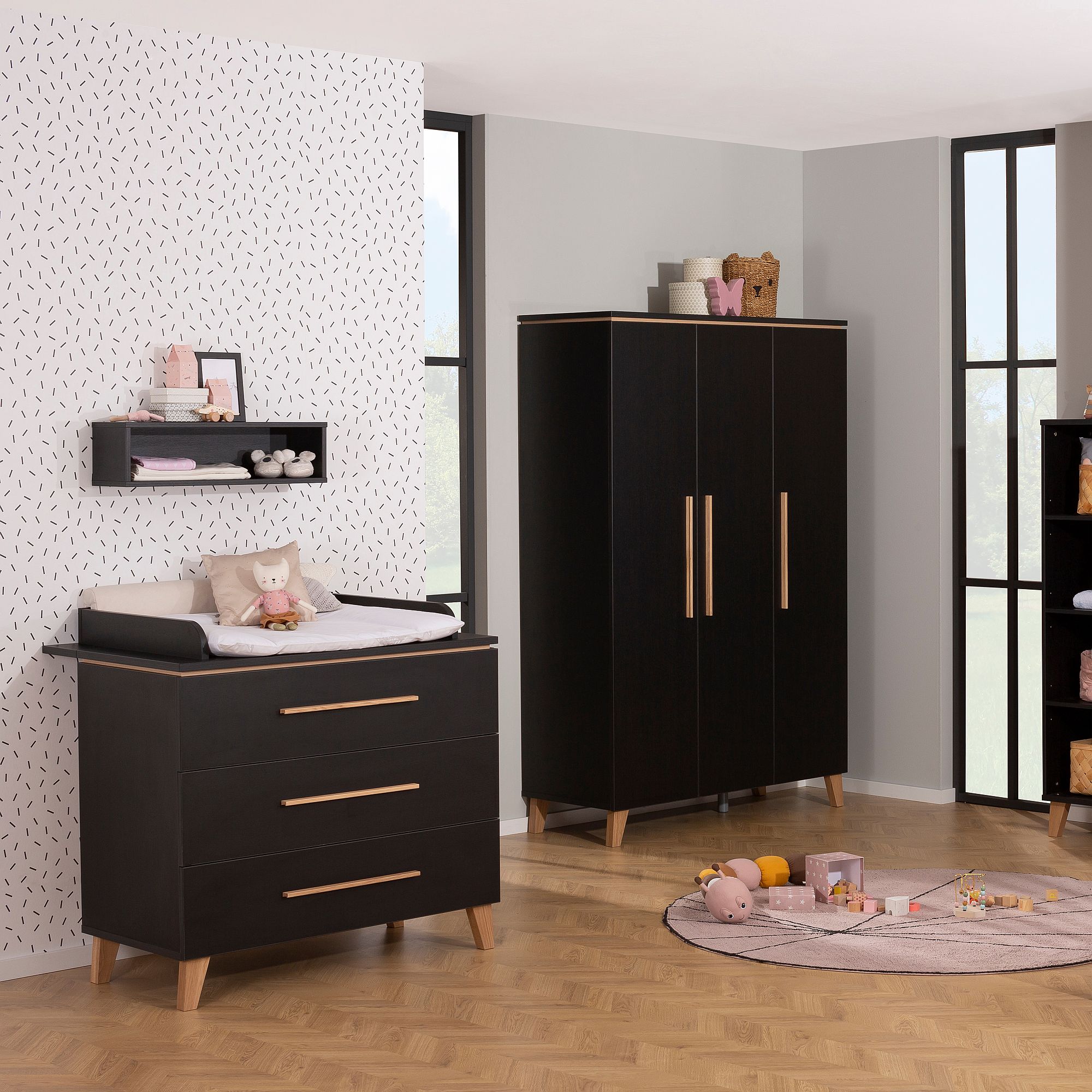 Modernes Kinderzimmer mit dunklen Holzmöbeln, Spielzeug und einem Wickeltisch vor einer gemusterten Wand.
