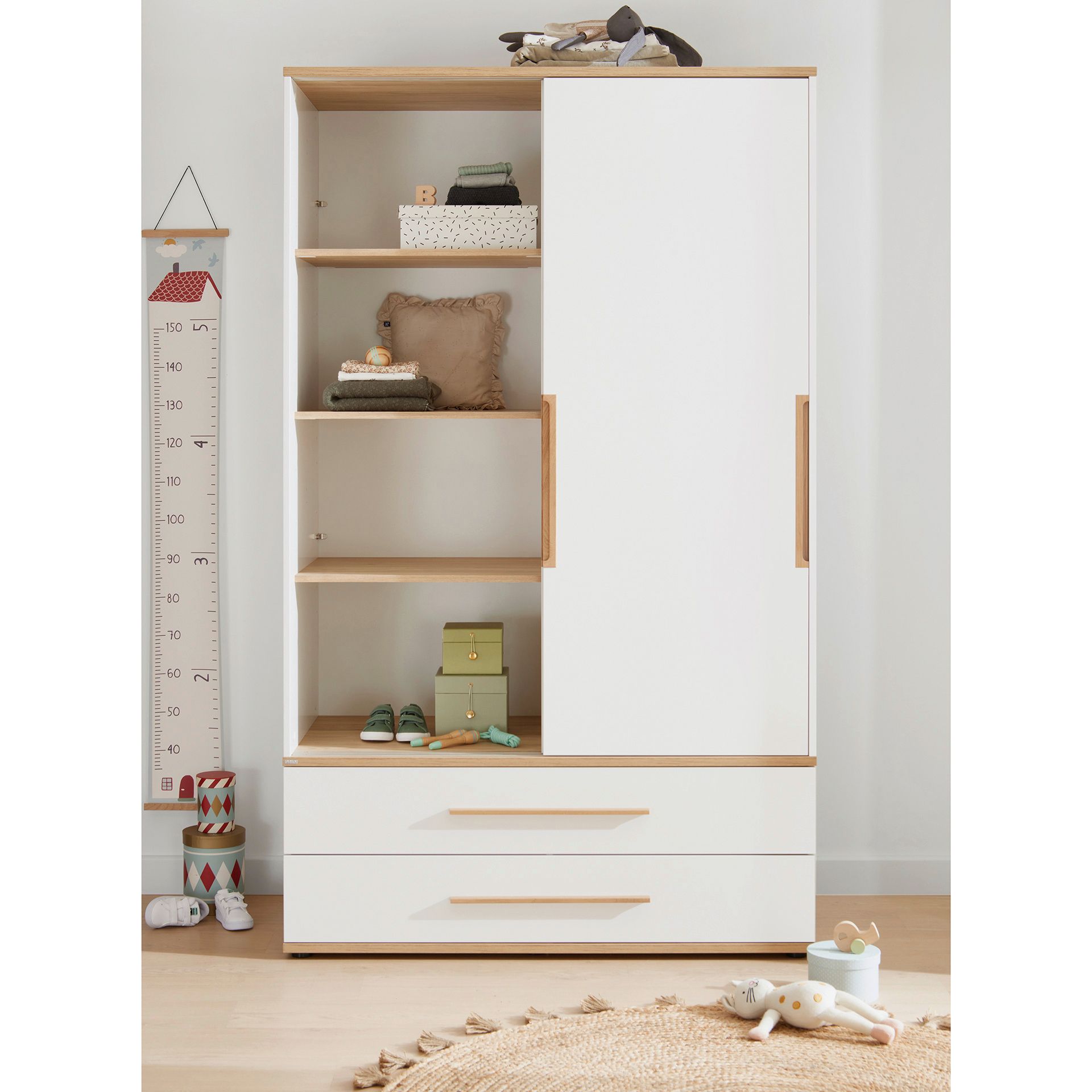White and wood wardrobe with shelves, drawers, toys, and a height chart nearby.