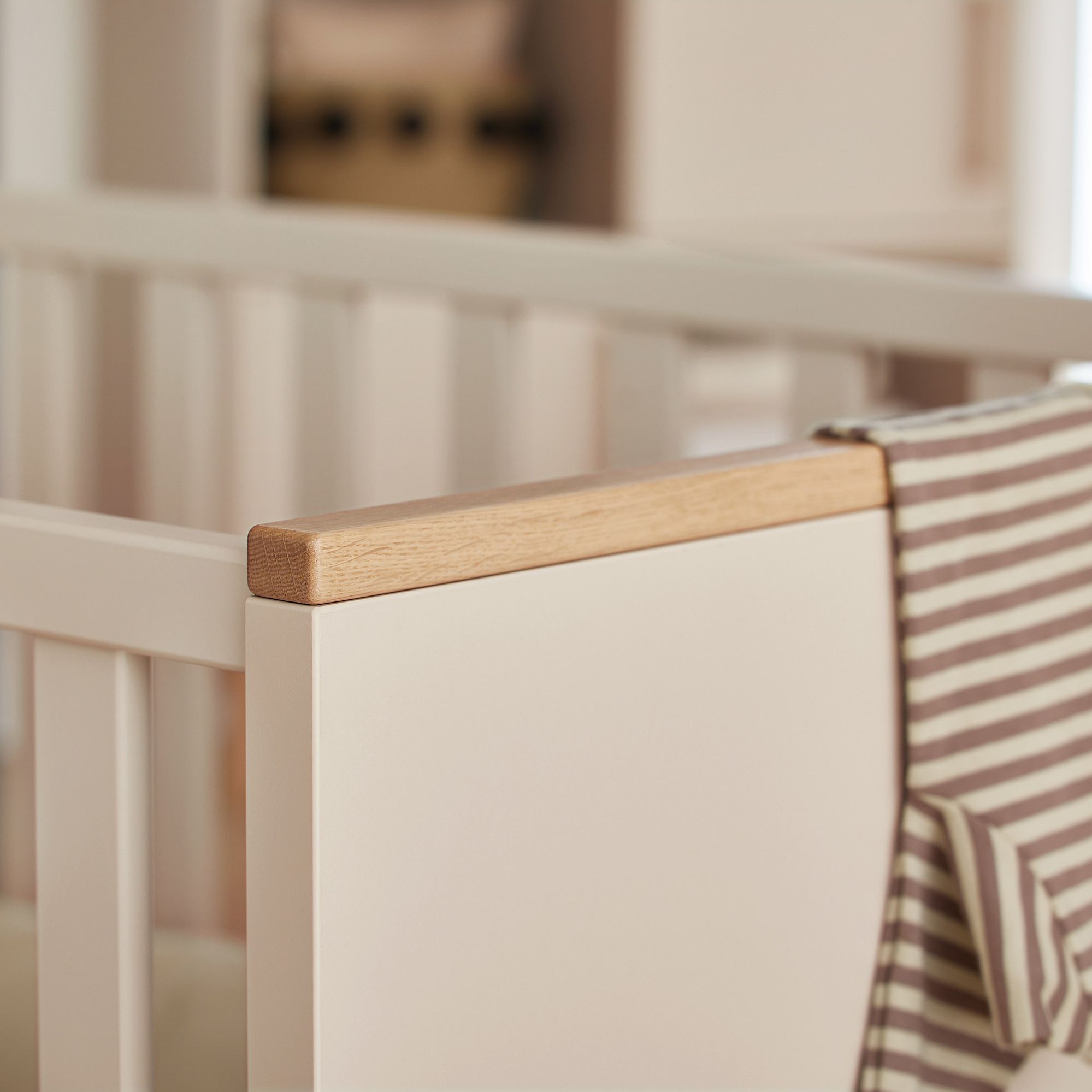 Nahaufnahme einer Krippenecke mit einer gestreiften Decke, die über den Rand drapiert ist.