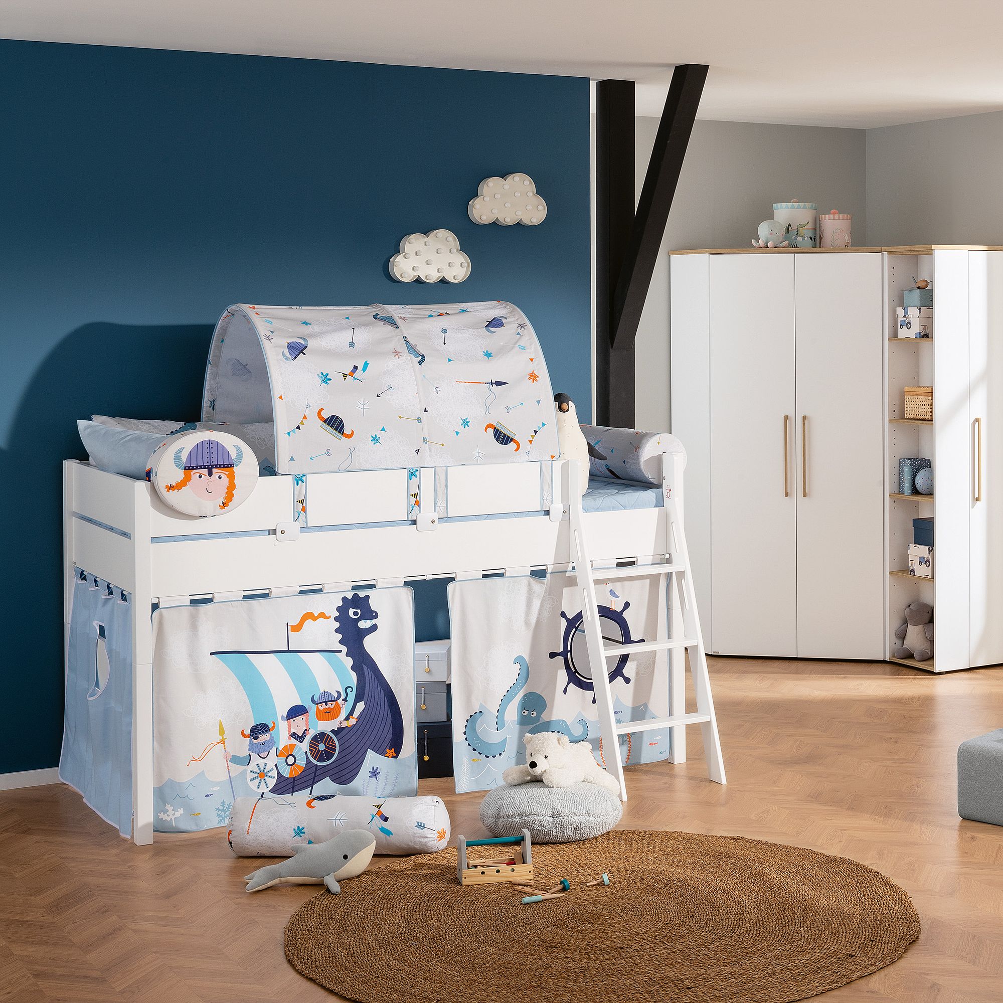Kids bedroom with a Viking themed loft bed, toys, and blue accent wall.