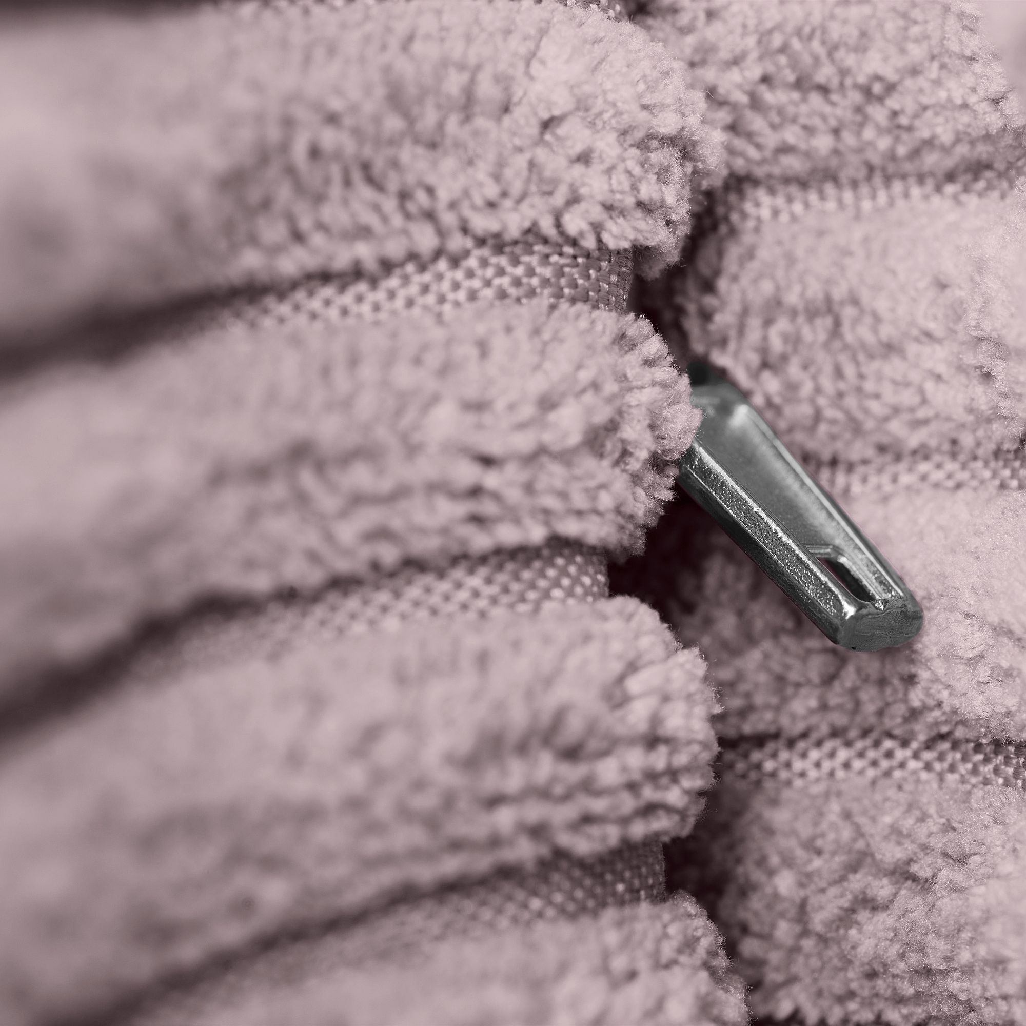 Ein Metallreißverschluss, eingebettet zwischen Lagen aus weichem, strukturiertem, rosa Stoff.