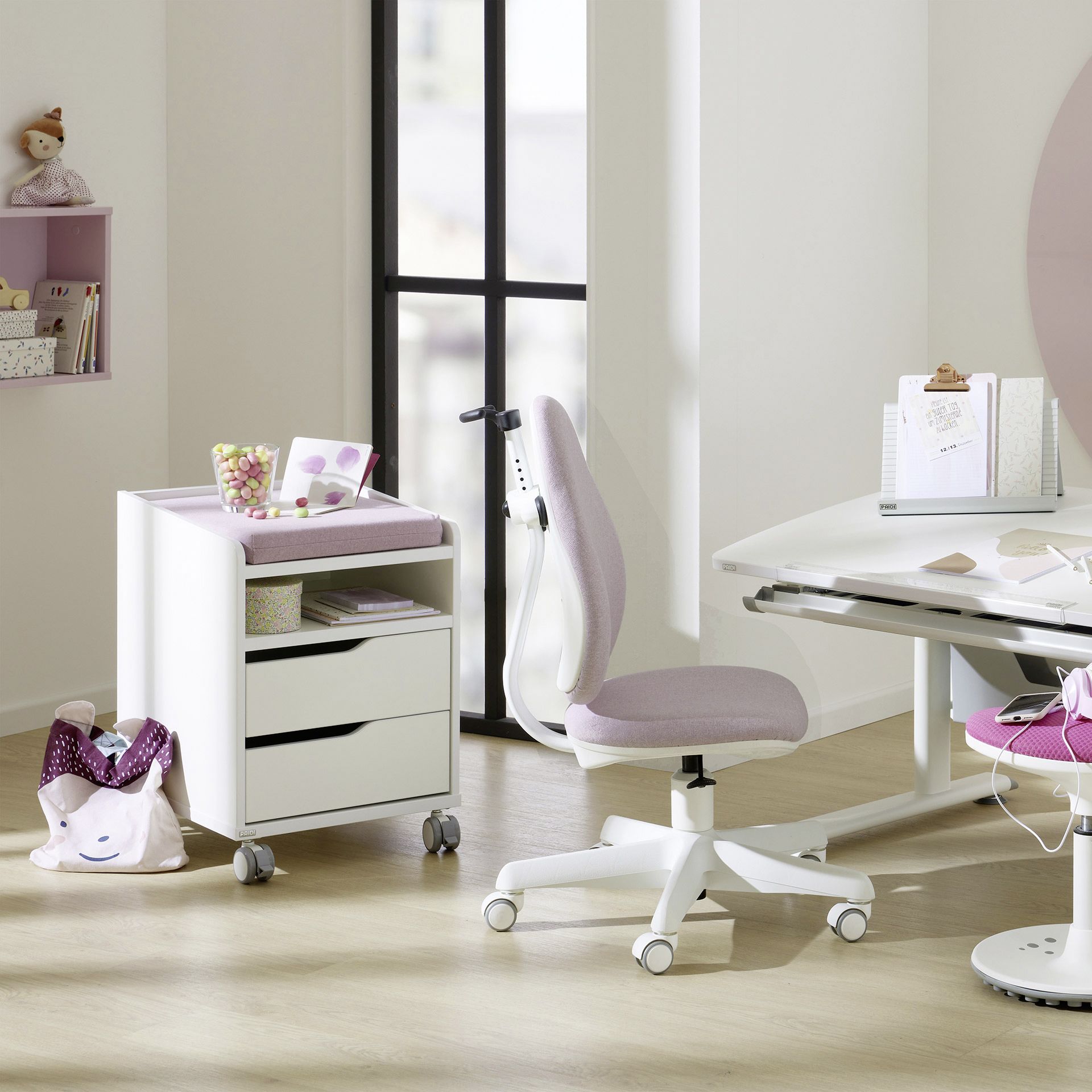Modern home office with a white desk, purple chair, and storage unit on wheels.