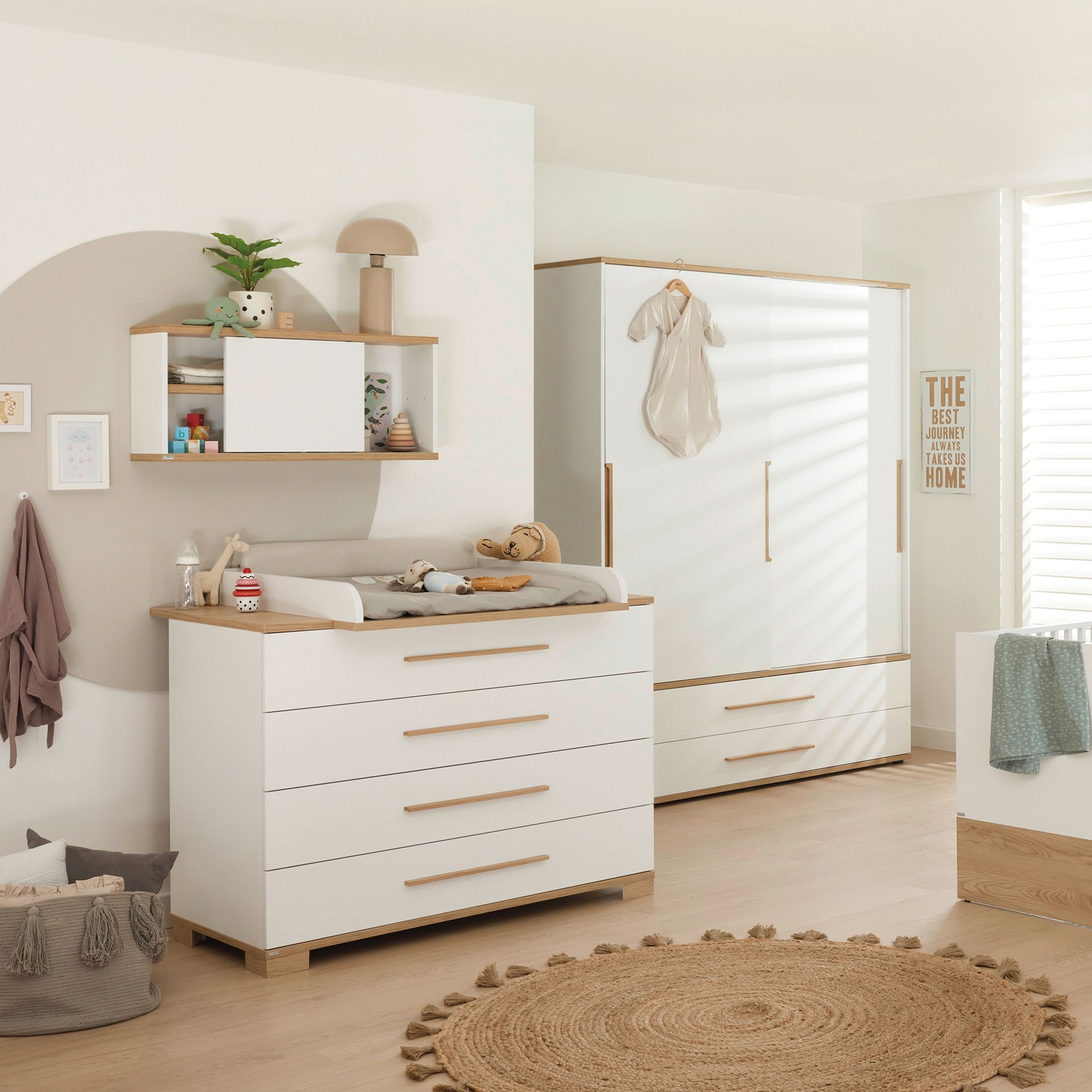 Modern nursery with white furniture, neutral decor, toys, and a hanging baby outfit.