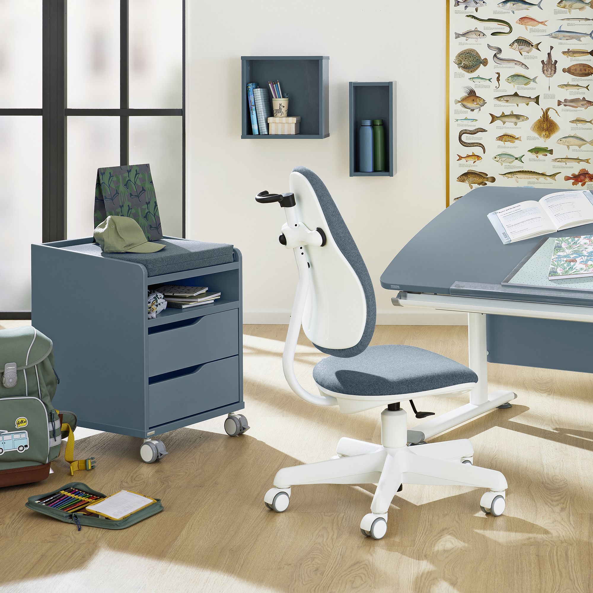 Modern study room with a blue chair, desk, rolling cabinet, and fish poster.