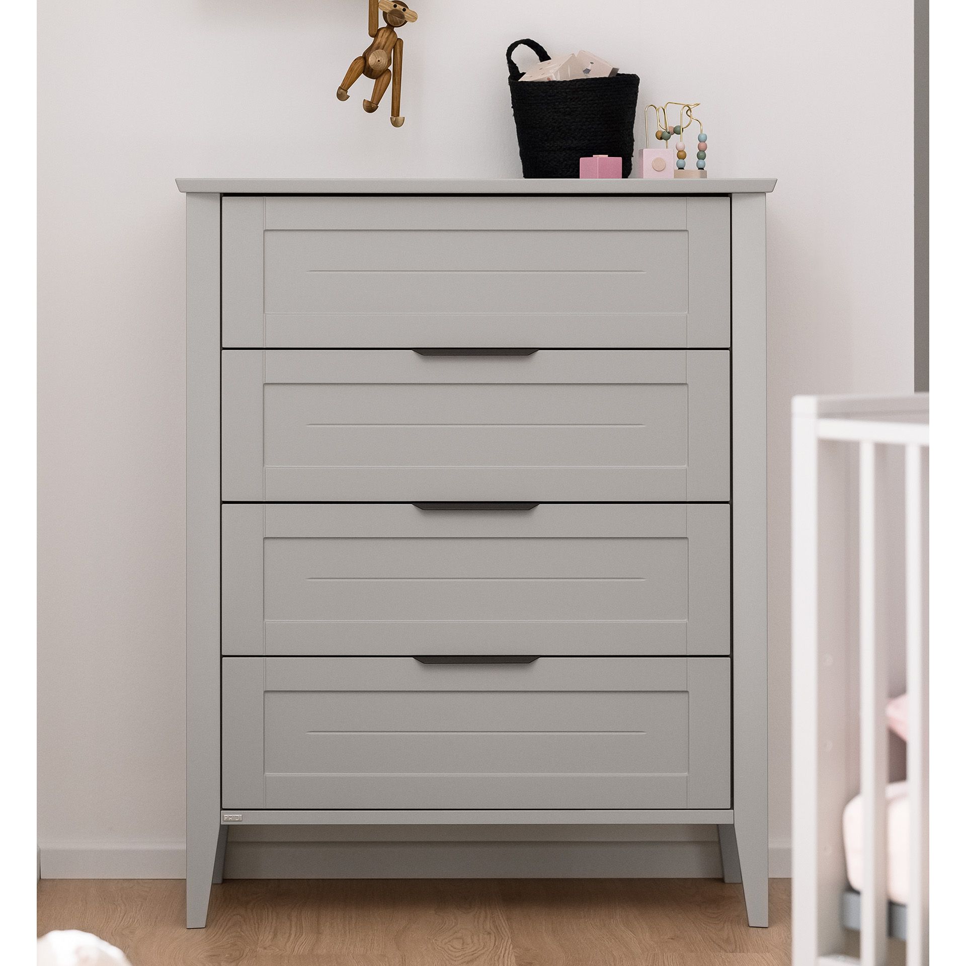 A light gray dresser with four drawers in a nursery room.