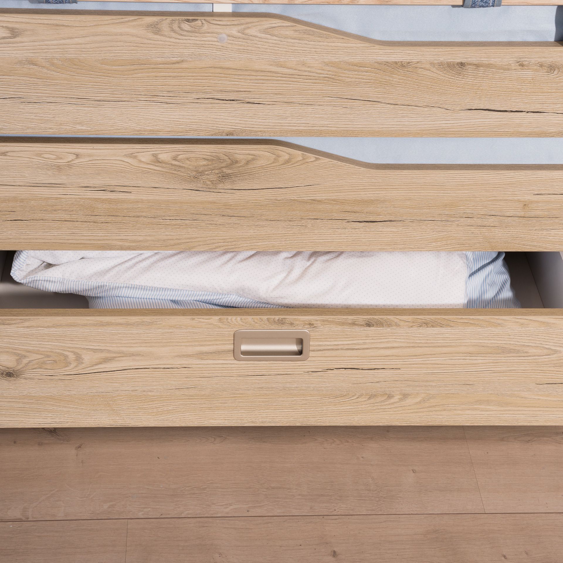 Holzbett mit einer ausziehbaren Schublade, unter der sich ein weißes Kissen befindet.