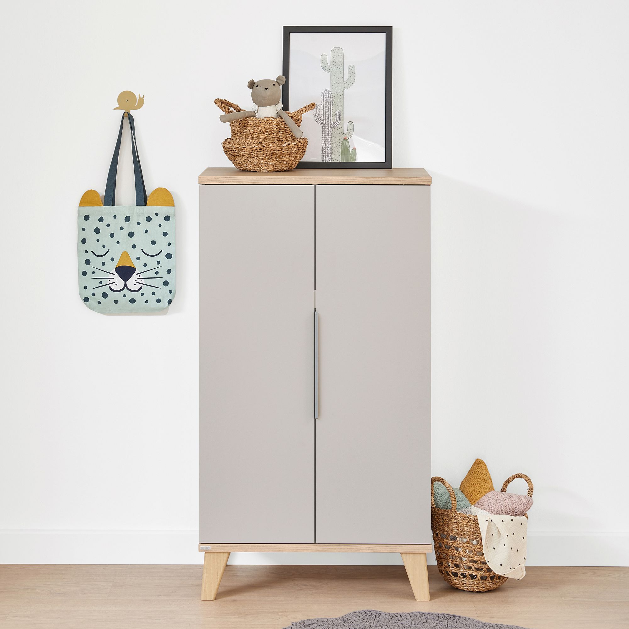 Modern cabinet with decor items, animal-themed bag, and baskets on a white wall.