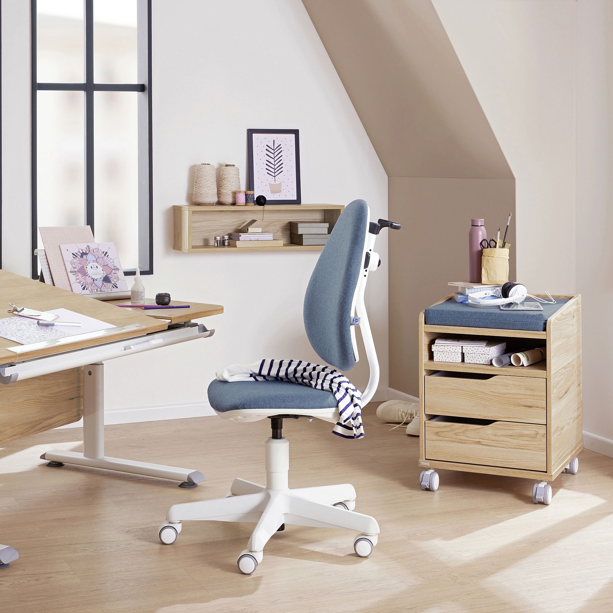 Modern home office with a blue chair, desk, drawers, and minimal decor.