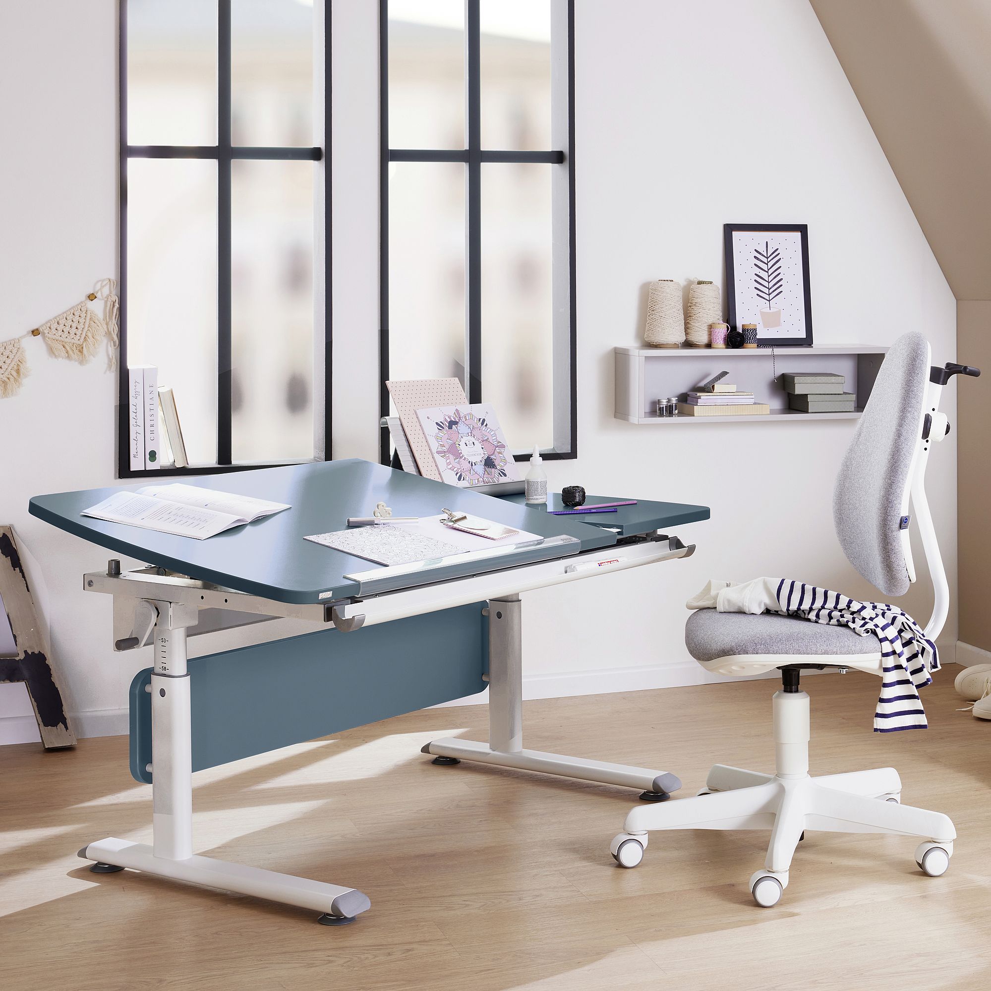 Schülerschreibtisch Diego GT Curved 130 x 70 cm, Mattblau Modern study desk with papers, art supplies, and a grey office chair nearby.