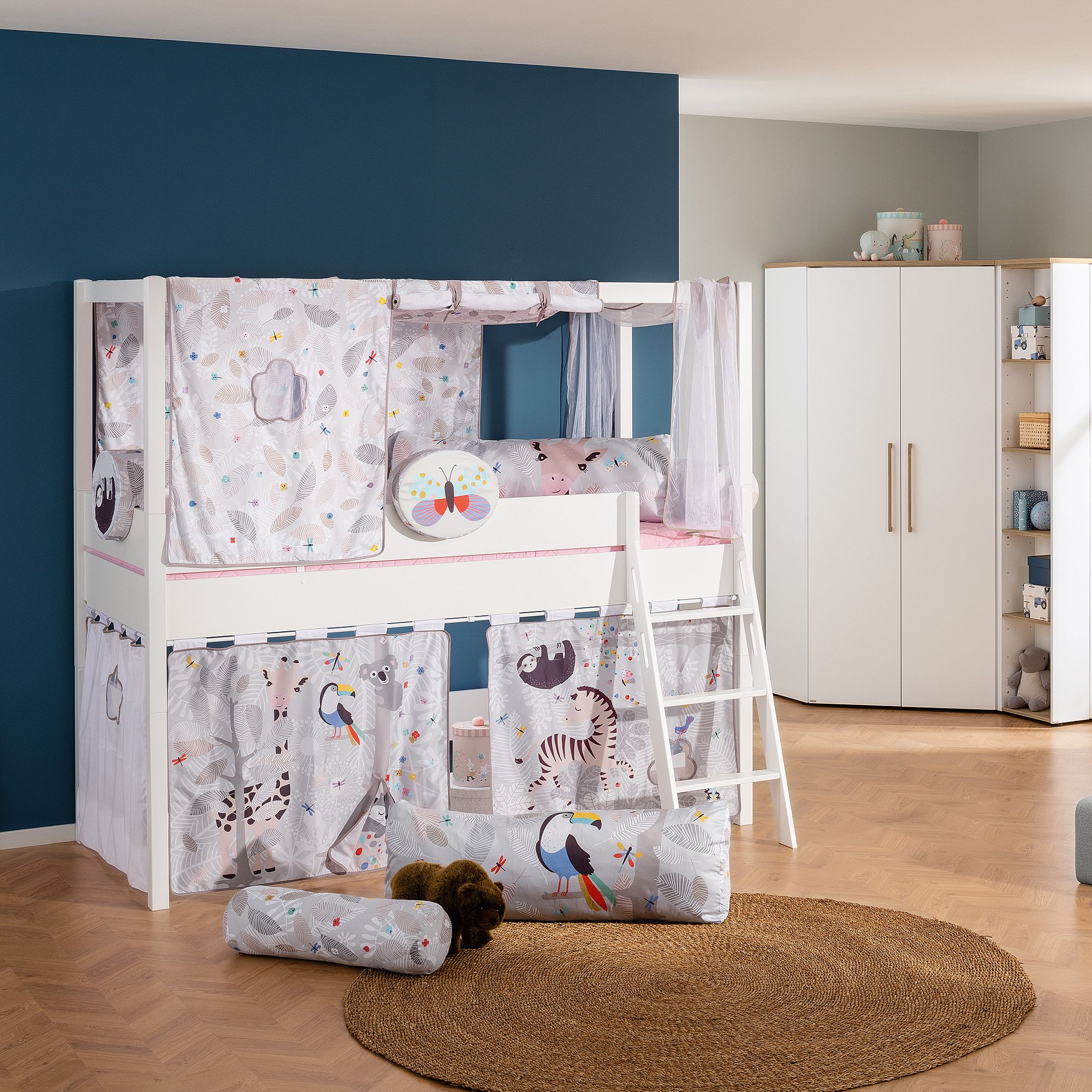 Children’s loft bed with animal-themed curtains, ladder, and cozy decor in a bedroom.