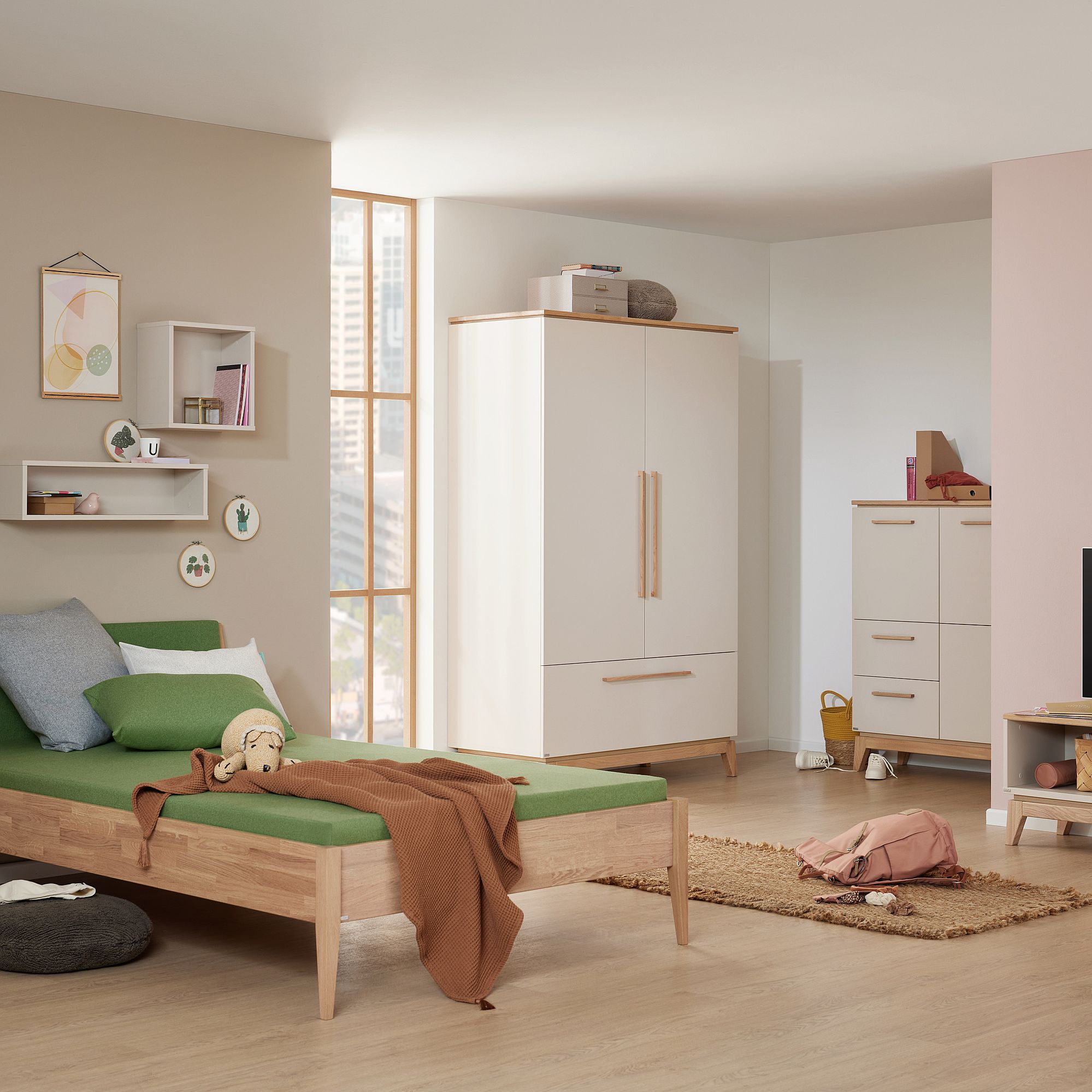 Ein aufgeräumtes Schlafzimmer mit einem grünen Bett, einem Kleiderschrank, einer Kommode und Regalen an der Wand.