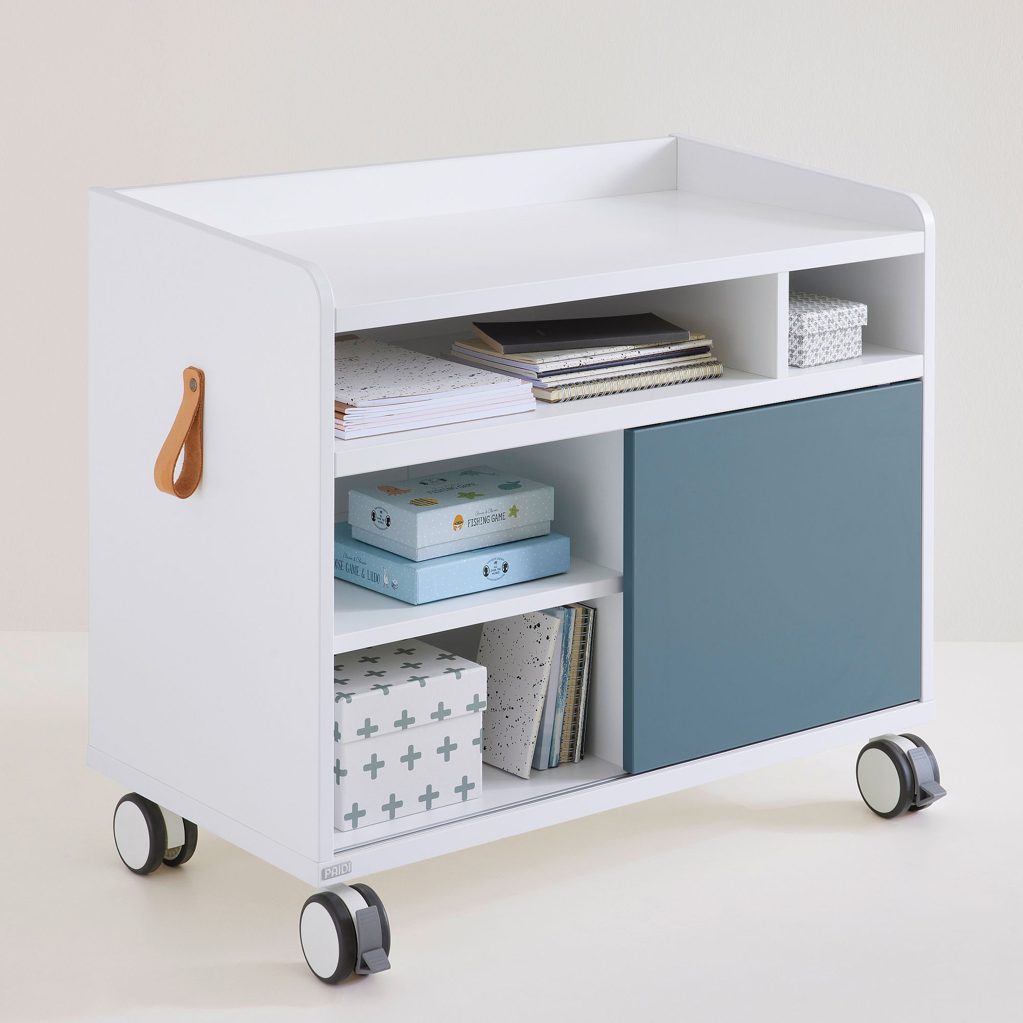 Rollcontainer Rollcaddy mit 1 Schiebetür in Mattblau Weißer rollender Aufbewahrungswagen mit Regalen, Büchern, Kisten und einer blauen Schranktür.