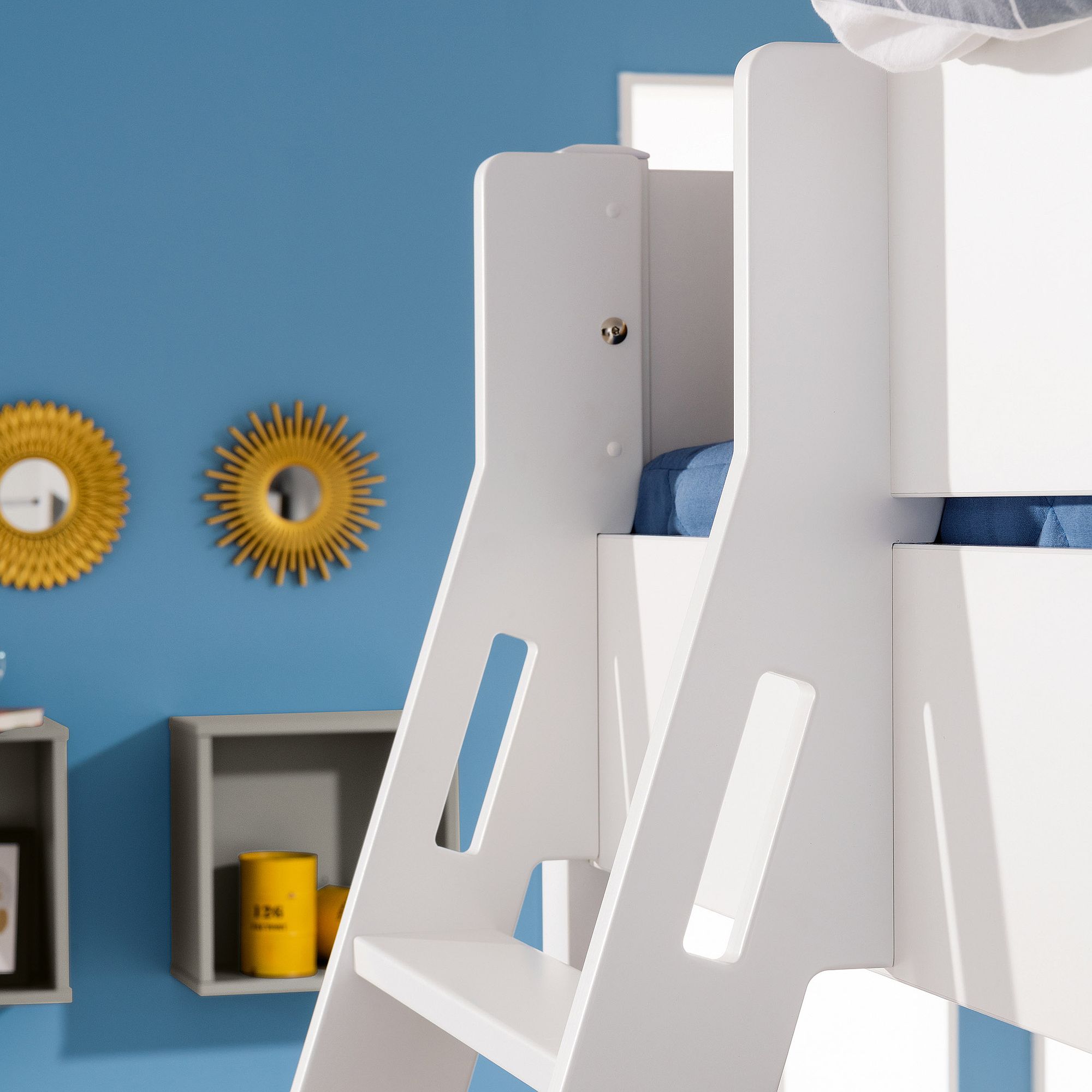 Weiße Etagenbettleiter vor einer blauen Wand mit Spiegeln und Regalen mit Sonnenschliff.