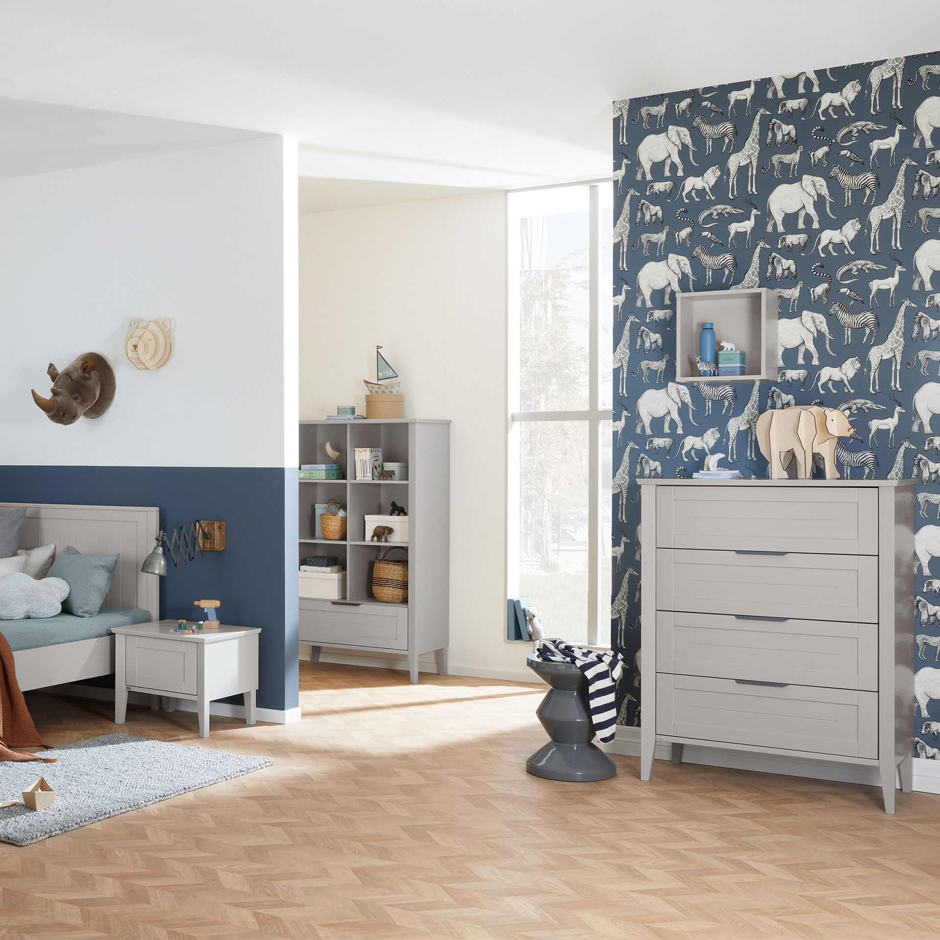Childrens bedroom with animal decor, gray furniture, and blue animal-print wallpaper.