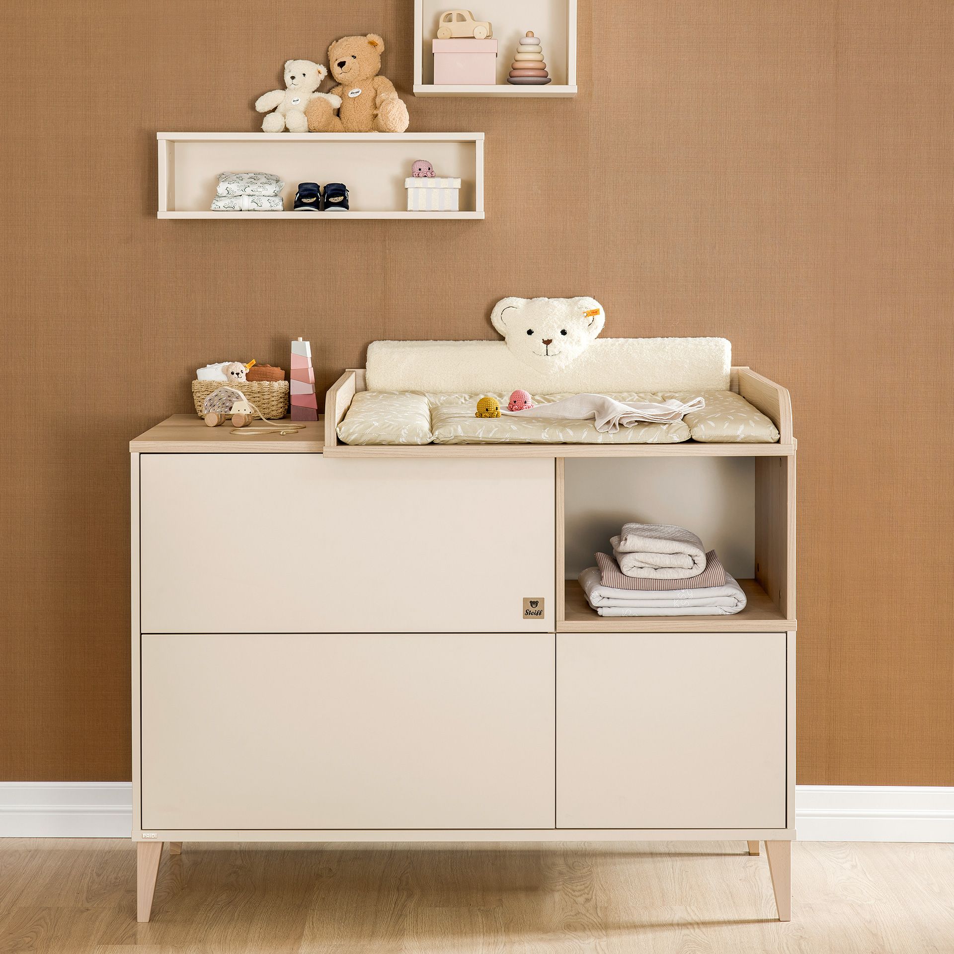 Beigefarbener Wickeltisch mit Babyartikeln, Regalen und Teddybären in einem Kinderzimmer.