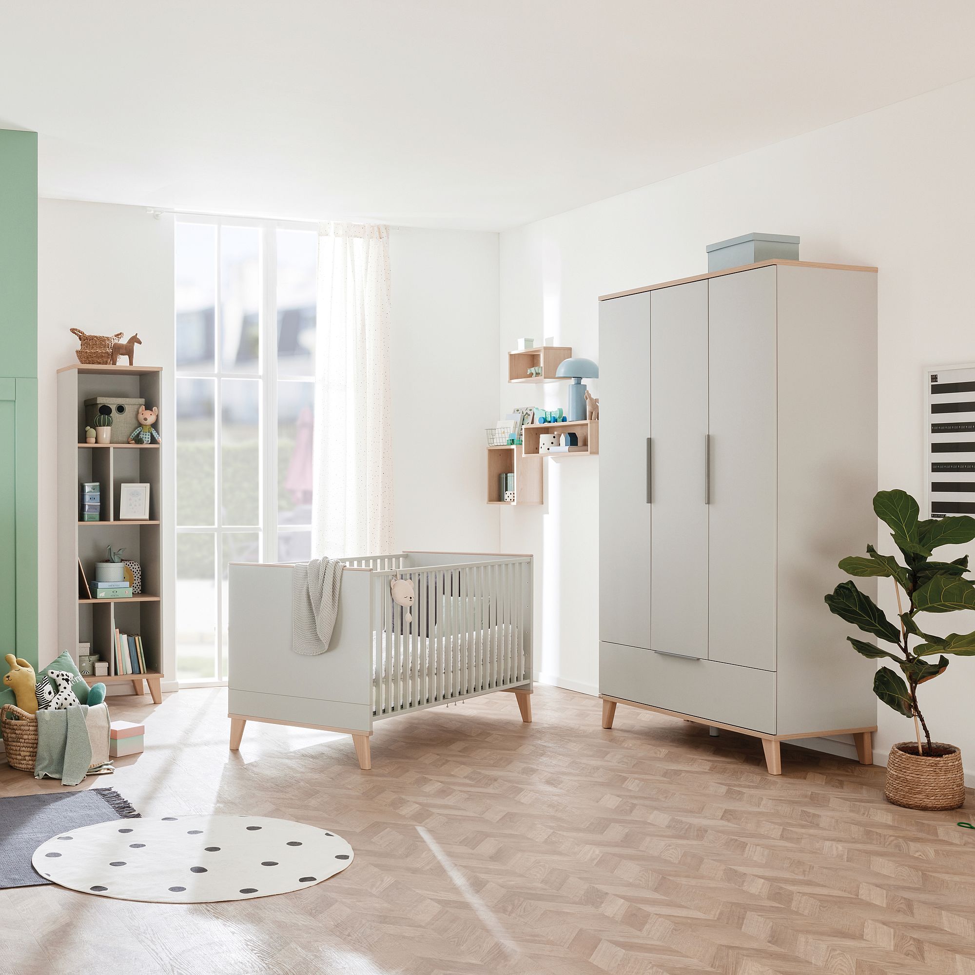 Modern nursery with a crib, wardrobe, bookshelf, and soft natural light.