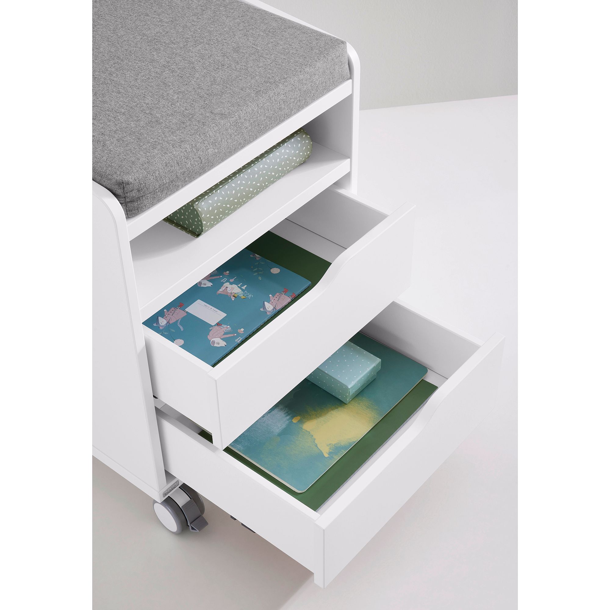 Rollcontainer  mit 2 Schubladen in Kreideweiß Weißer rollender Aufbewahrungswagen mit offenen Schubladen für Papiere und ein gefaltetes Tuch.