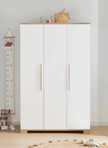 A white wardrobe with wooden accents opens to reveal neatly organized children’s clothes, shoes, and toys inside a bright room.